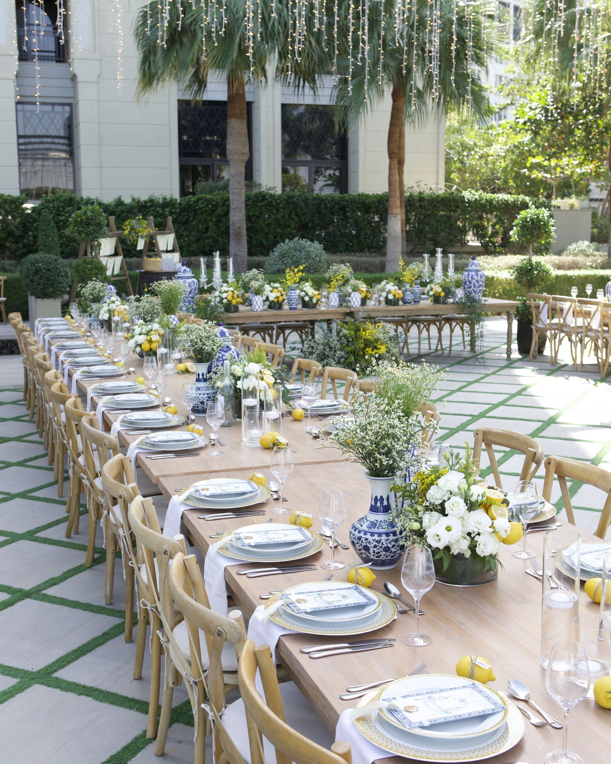 Courtyard view of crossback chairs along lemon-dressed tables under hanging string lights