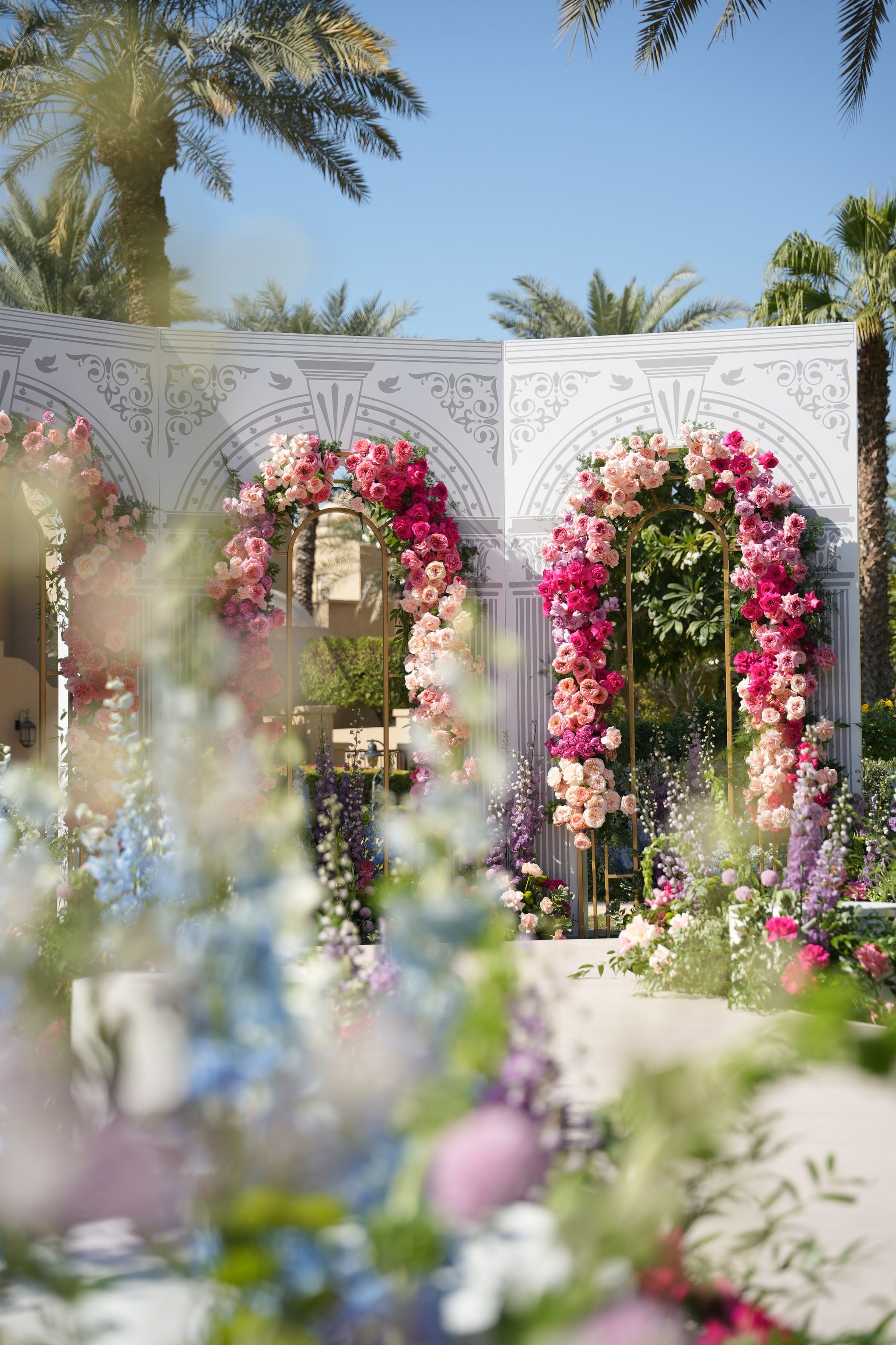 Rose arches in pink, coral and fuchsia seen through soft-focus delphiniums at One&Only Royal Mirage Dubai