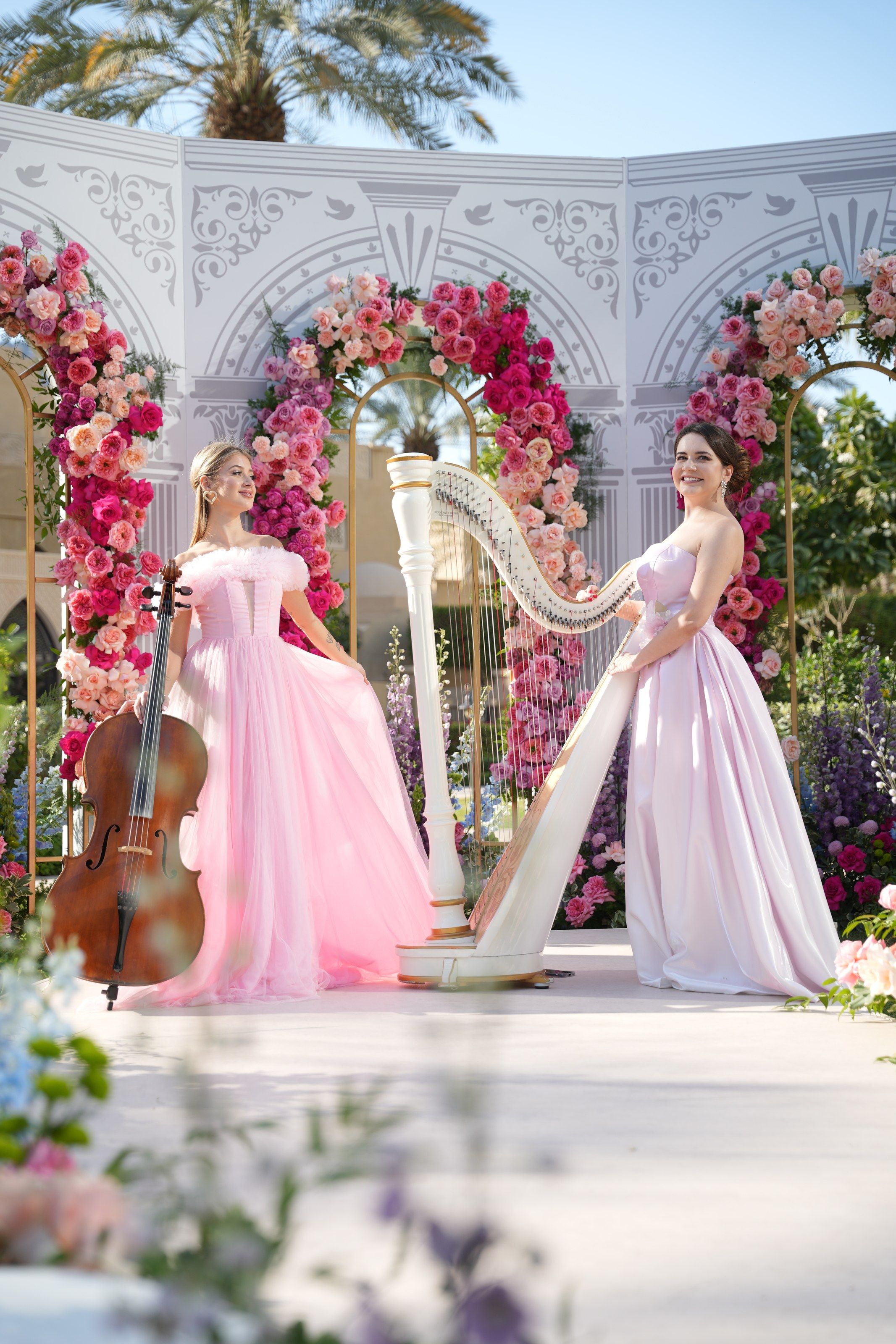 Cellist and harpist in blush tulle gowns before the rose-arched ceremony screen at One&Only Royal Mirage Dubai