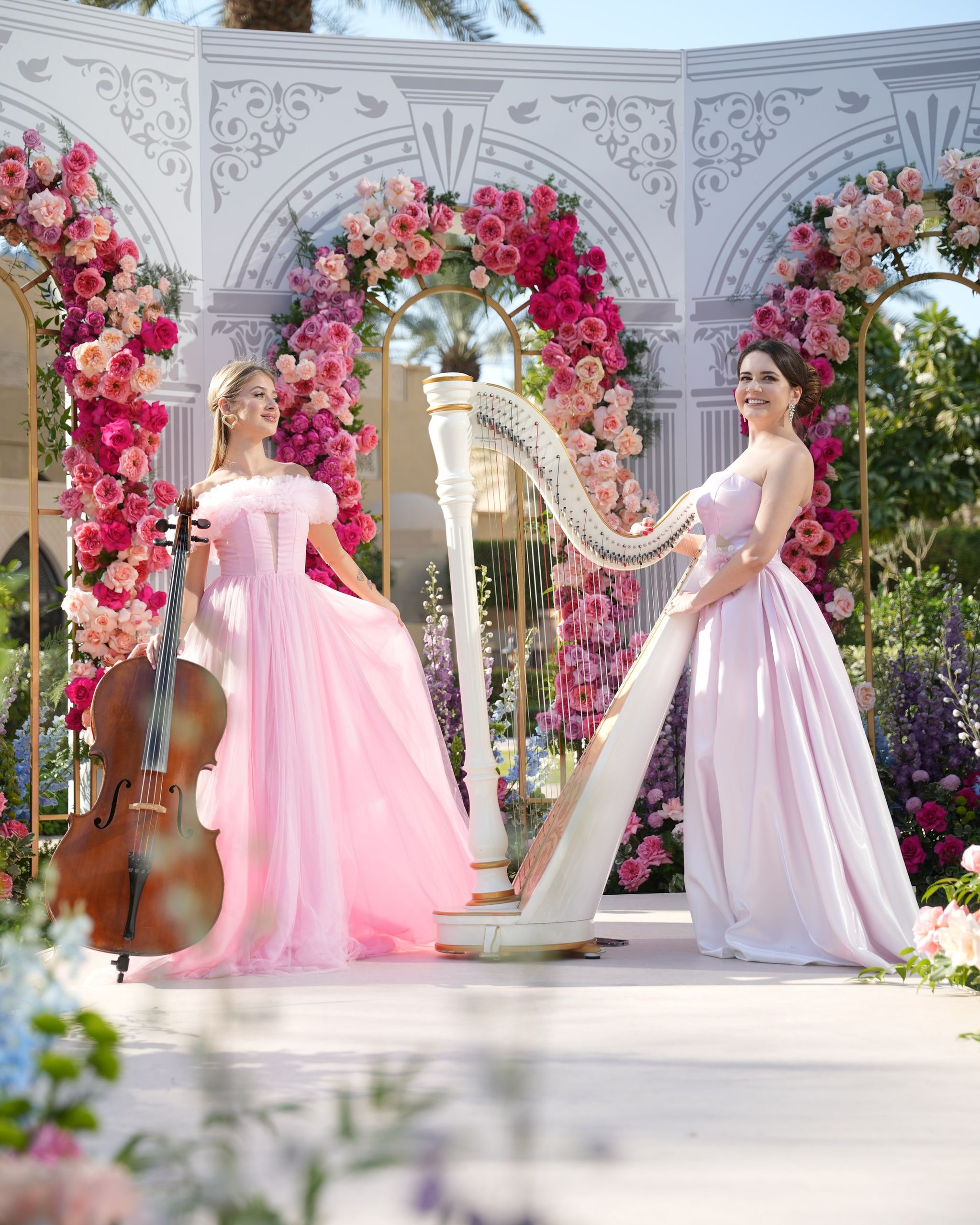 Cellist and harpist in blush tulle gowns before the rose-arched ceremony screen at One&Only Royal Mirage Dubai