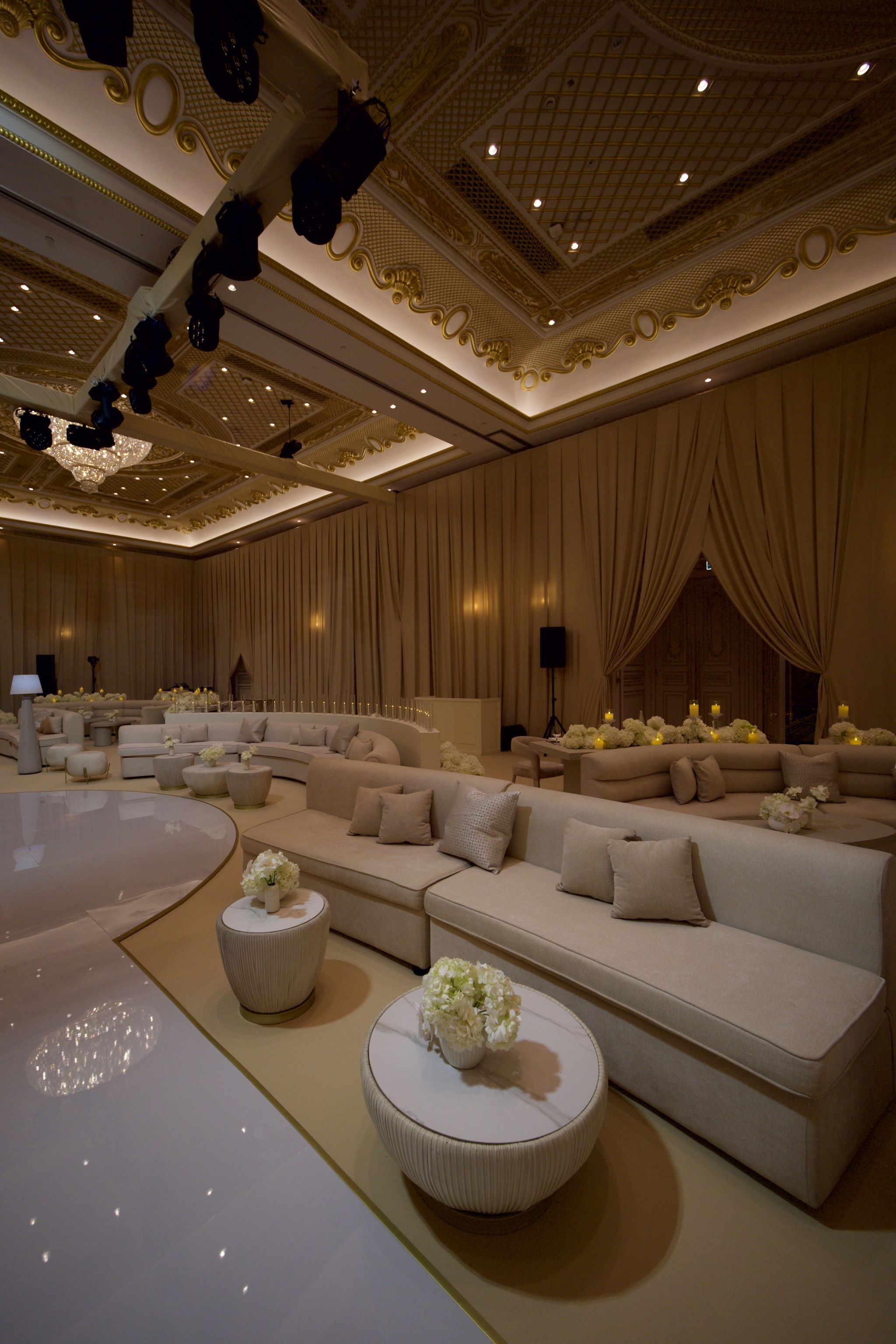 Ivory lounge seating with hydrangea side tables beneath the gilded coffered ceiling of the ballroom at Raffles The Palm Dubai