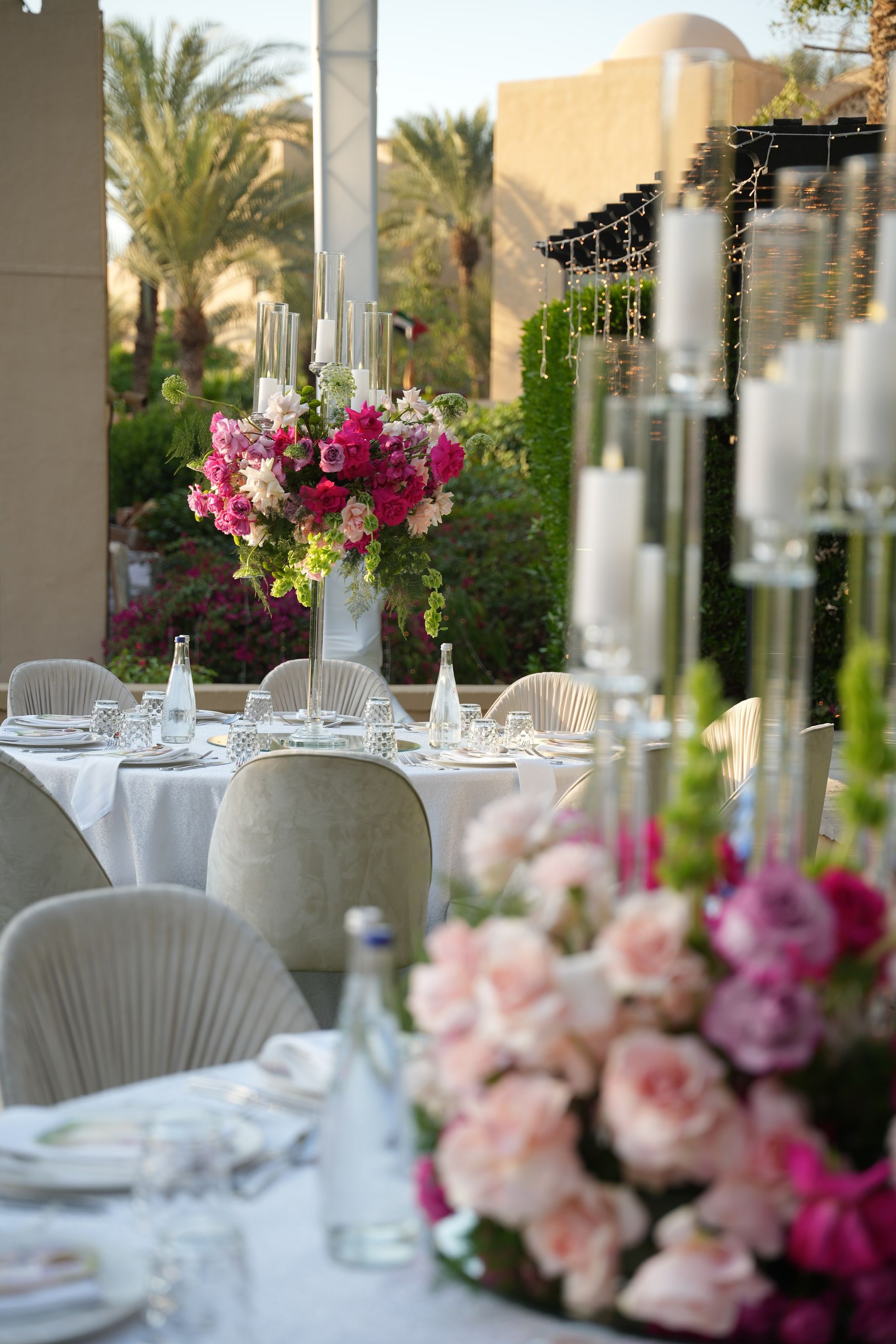 Candlelit tables with blush roses in the foreground and tall pink arrangements beyond