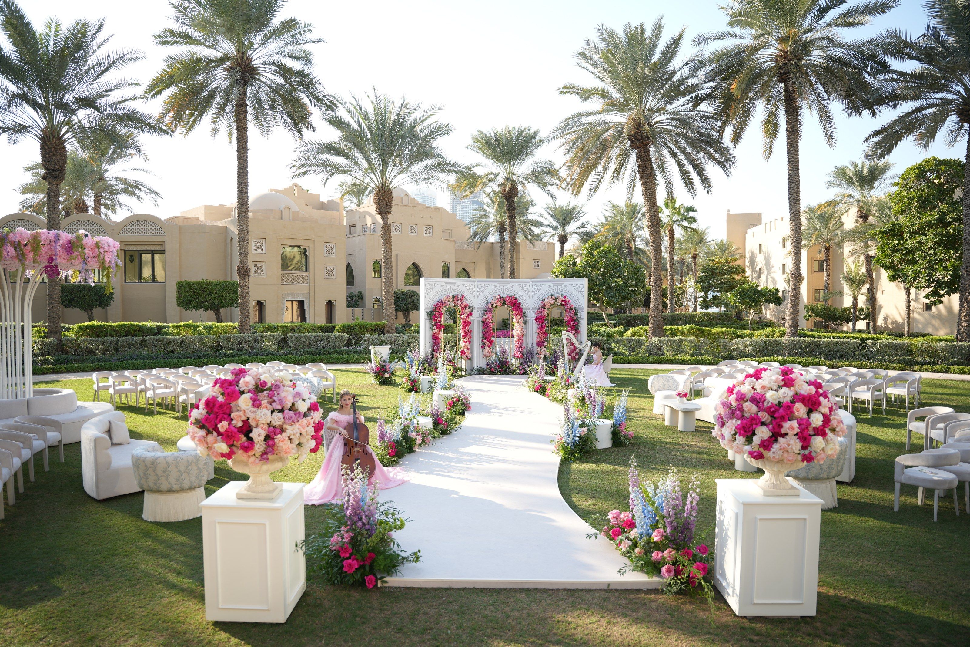 Garden ceremony aisle with rose arches, urn arrangements, cellist and harpist at One&Only Royal Mirage Dubai