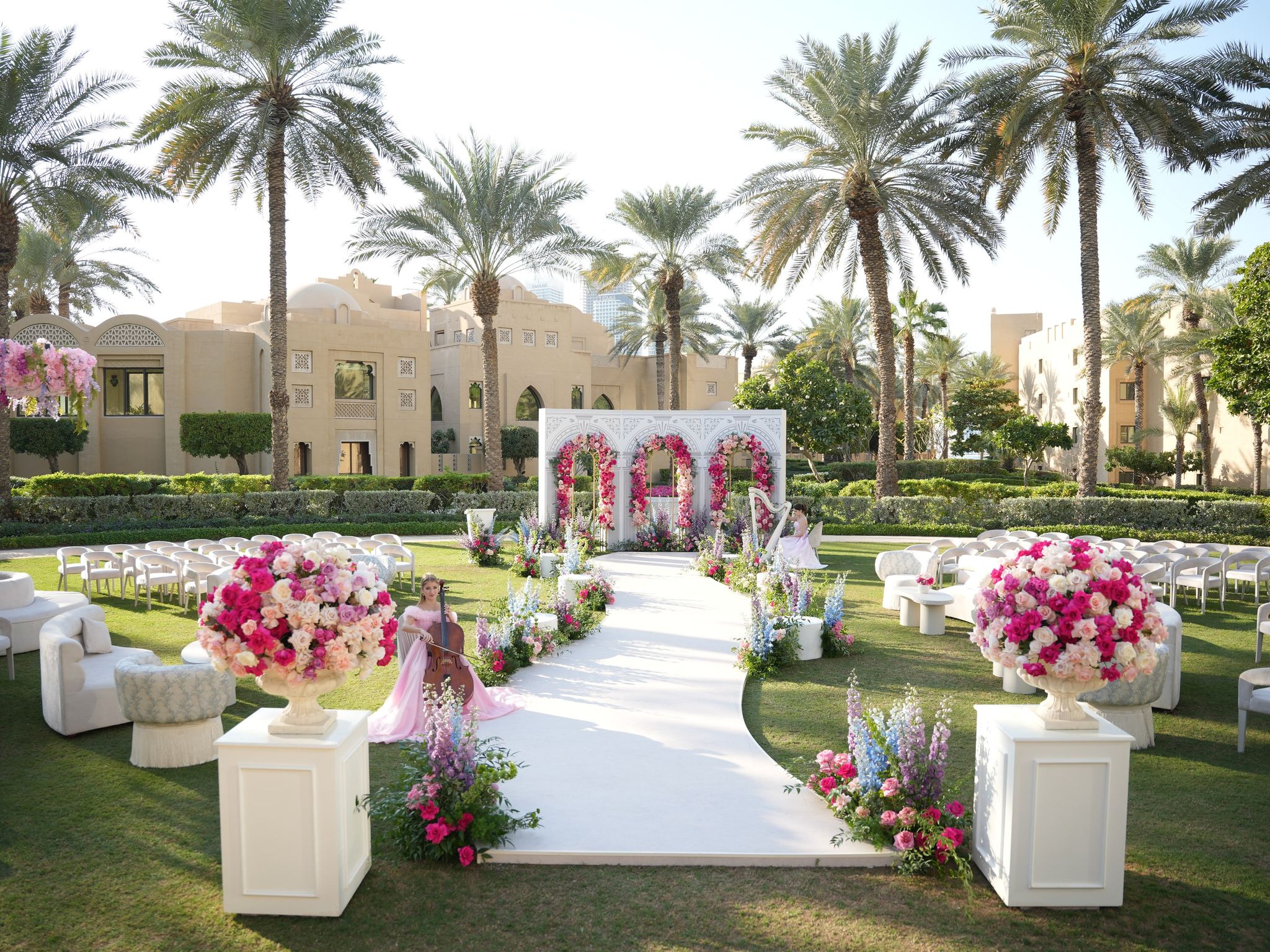 Garden ceremony aisle with rose arches, urn arrangements, cellist and harpist at One&Only Royal Mirage Dubai