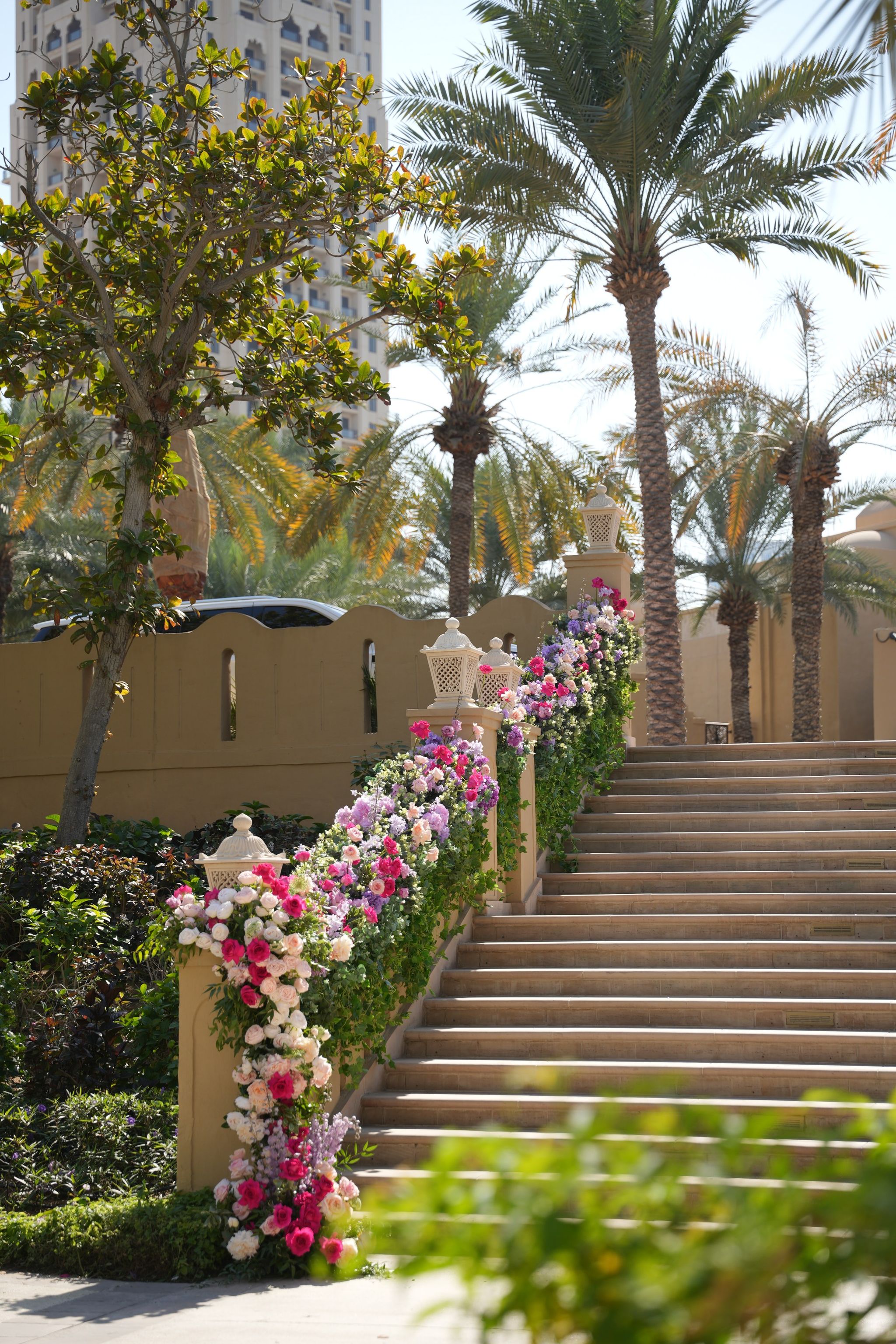 Garland of pink, white and lilac roses climbing a sandstone staircase beneath palm trees