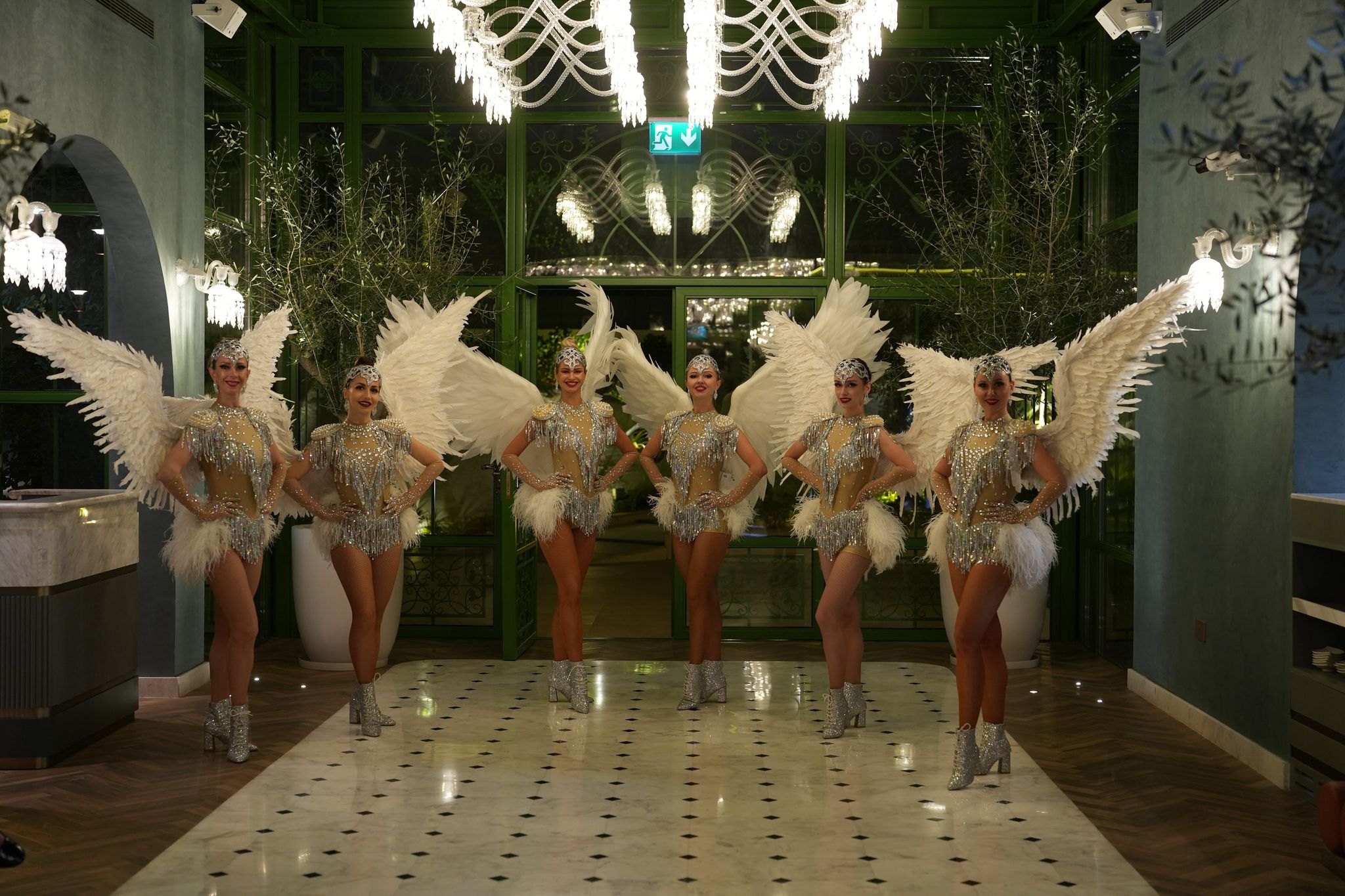 Six winged dancers in silver sequins inside the conservatory at Four Seasons Resort Dubai at Jumeirah Beach
