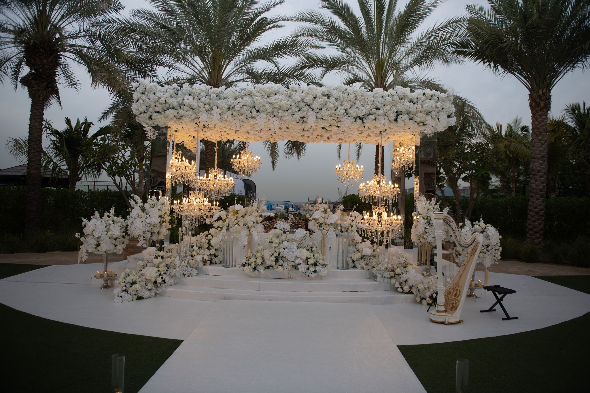 Floral canopy hung with crystal chandeliers beside a gilded harp at dusk, Four Seasons Resort Dubai at Jumeirah Beach