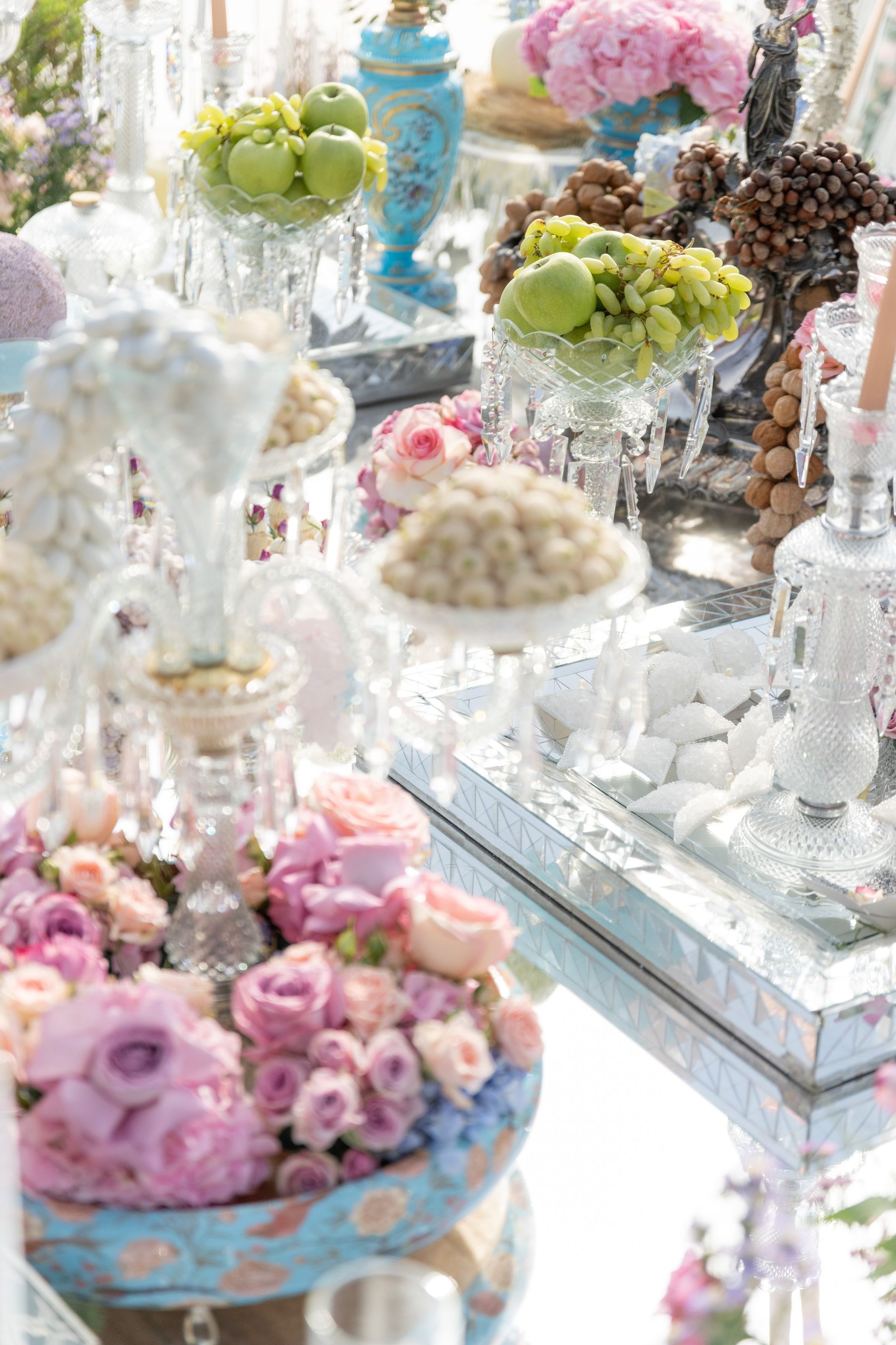 Green apples, grapes and sugared almonds in crystal dishes on a mirrored sofreh table