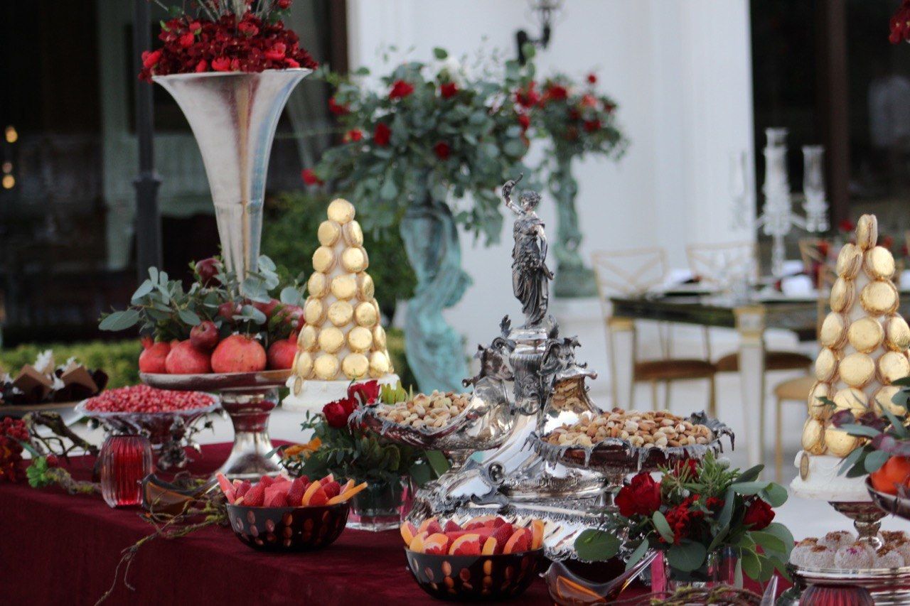 Silver centrepiece of pistachios and nuts with macaron towers, pomegranates and red roses
