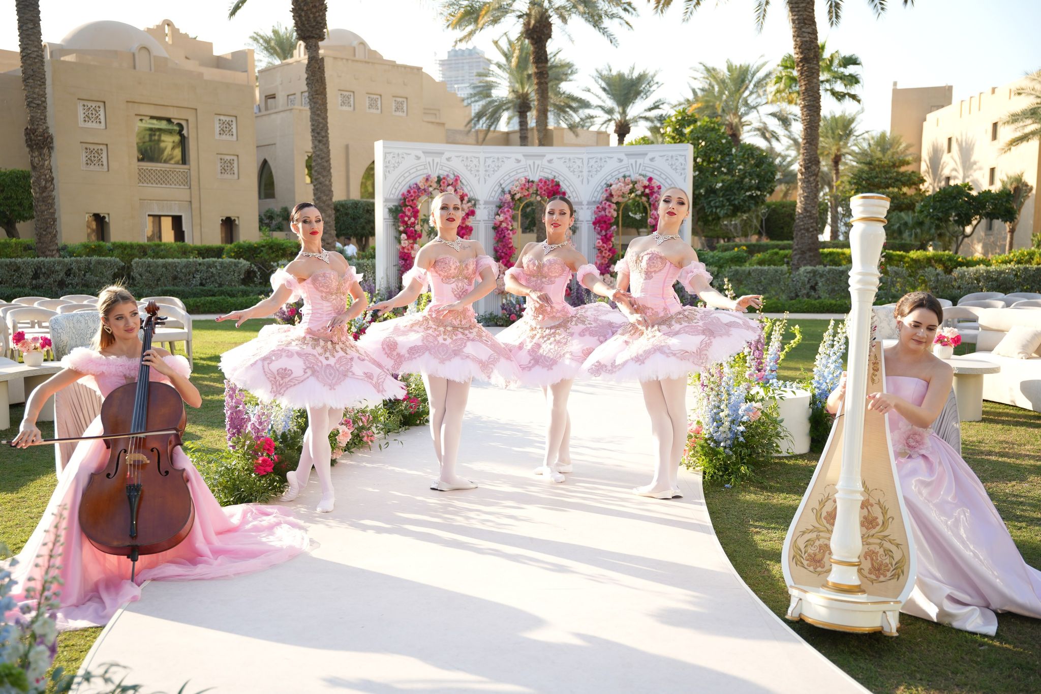 Four ballerinas in blush tutus between a cellist and harpist on the garden aisle at One&Only Royal Mirage Dubai