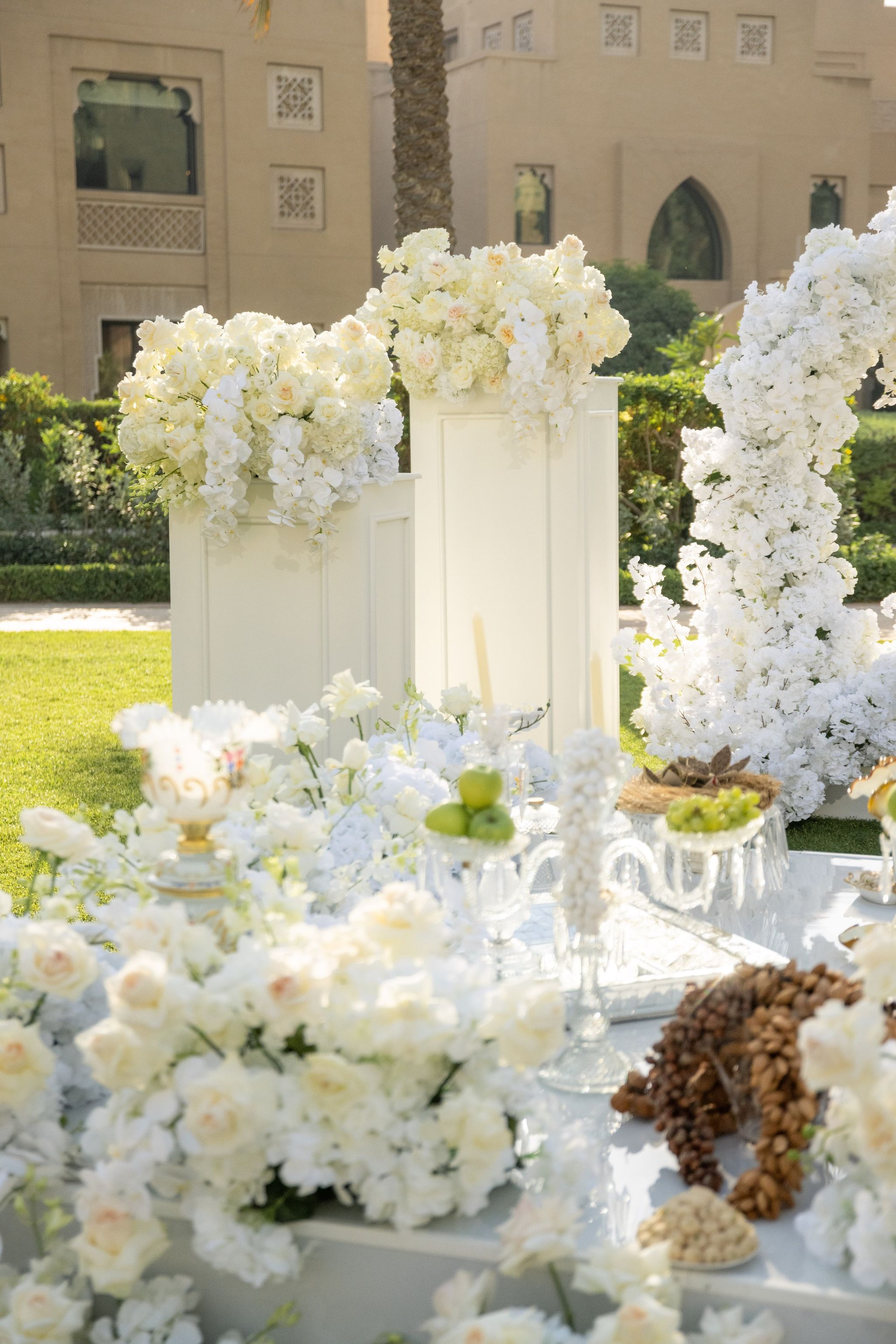 Sofreh aghd edged in white roses, with floral plinths and a cascading arch behind