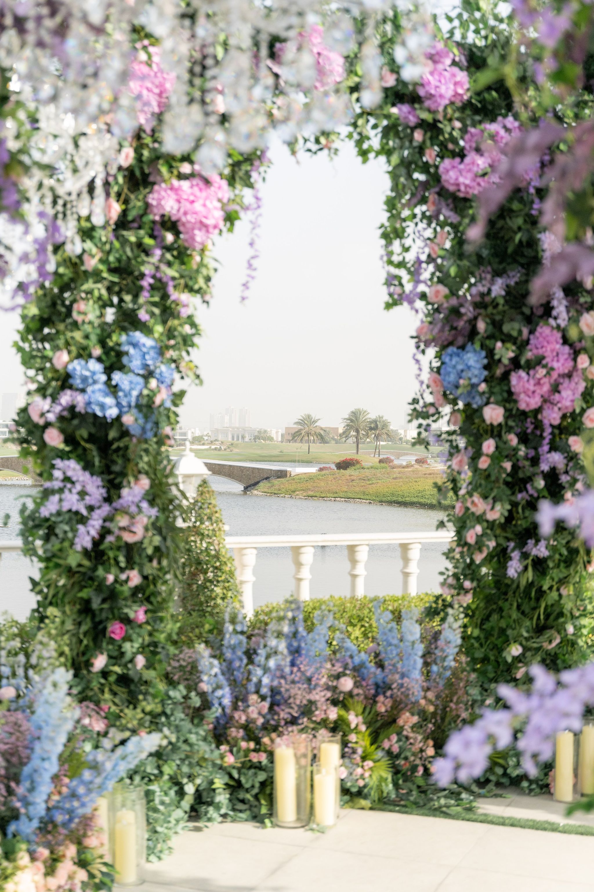 View through the wisteria and hydrangea canopy towards a lake, footbridge and distant palms