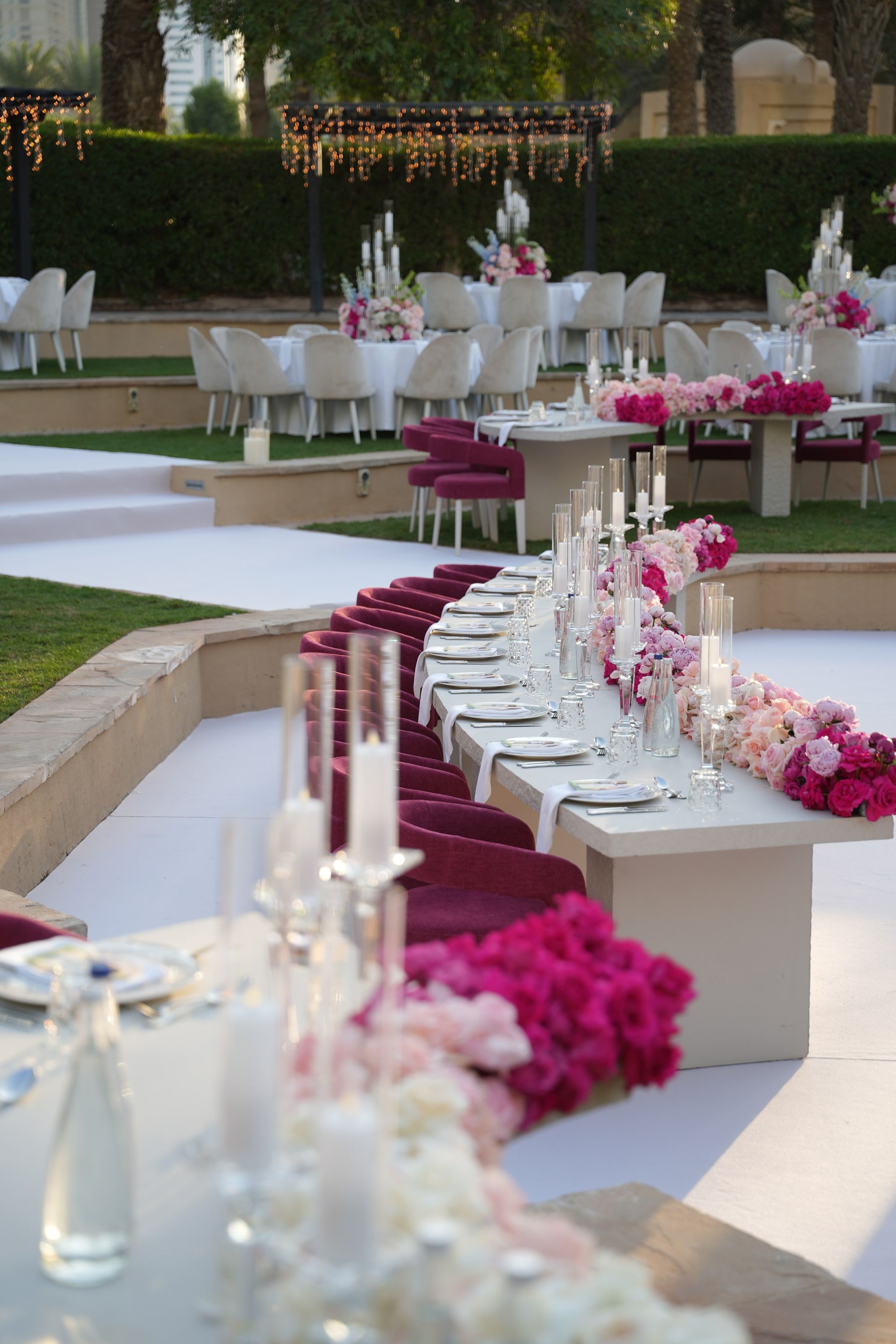 Long banquet table with magenta velvet chairs and a runner of pink and fuchsia roses