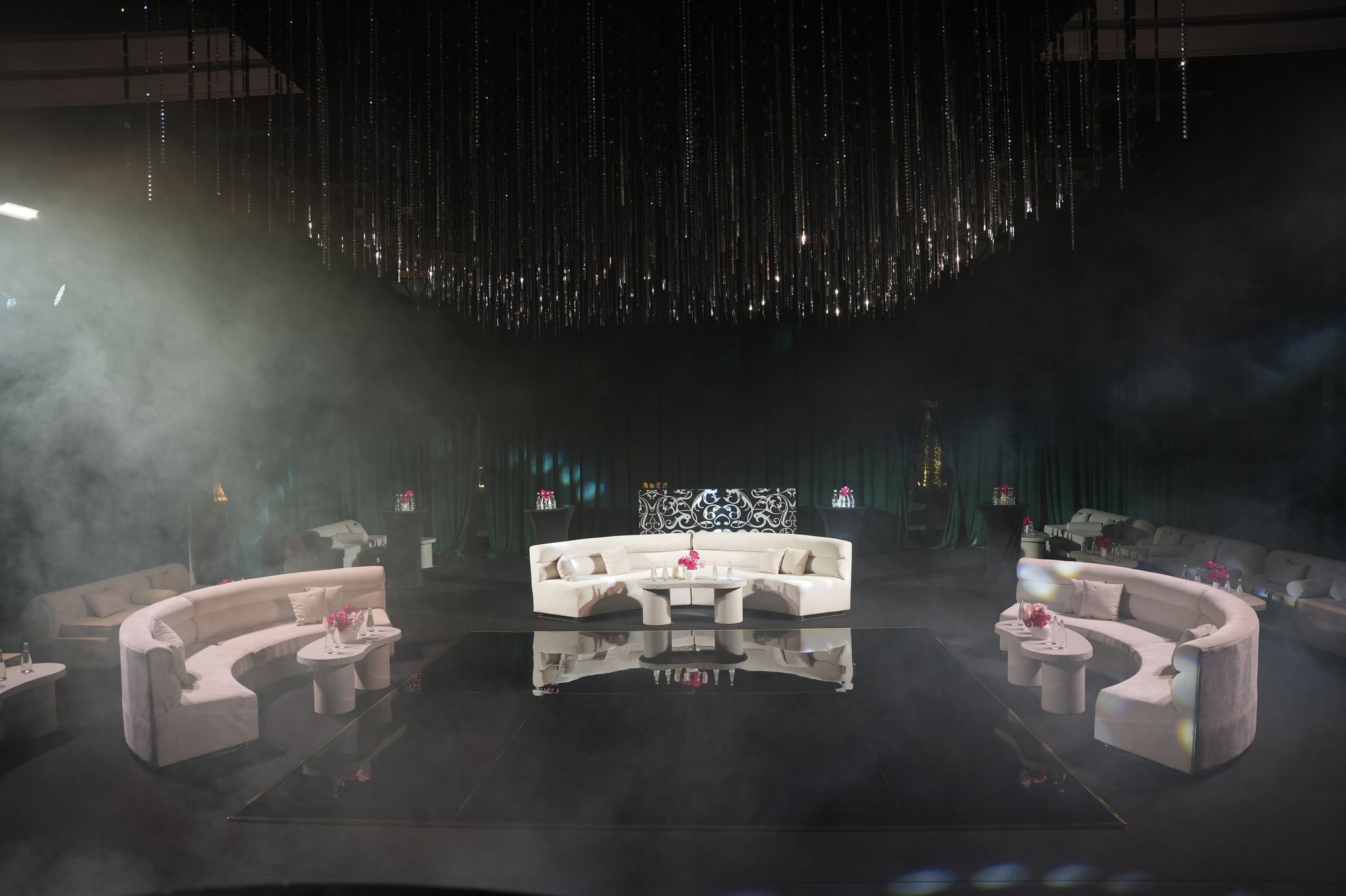 Evening lounge of curved ivory sofas around a mirrored floor under crystal strands at One&Only Royal Mirage Dubai