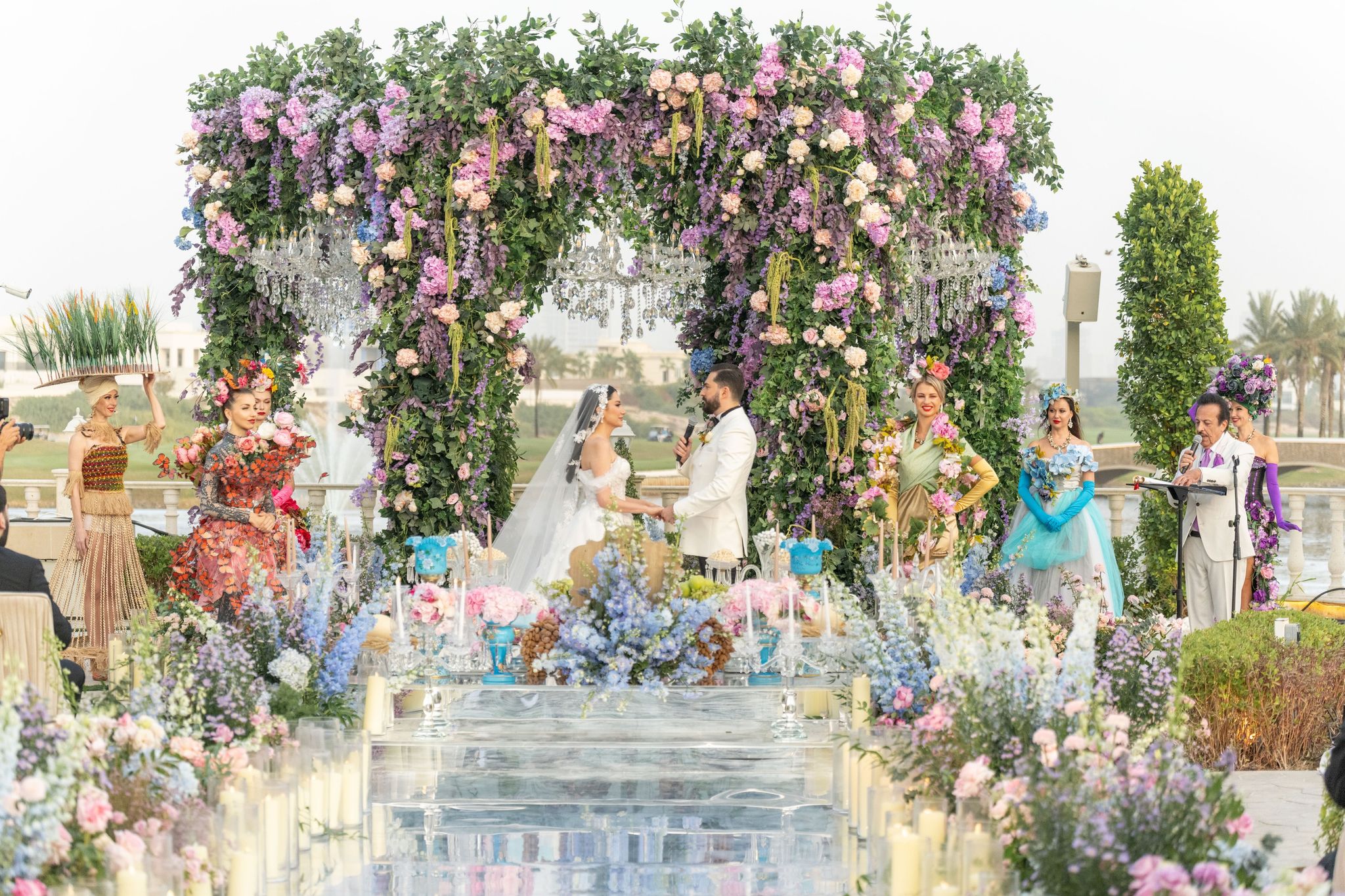 The bride and groom under the floral canopy, flanked by costumed performers, at Four Seasons Resort Dubai at Jumeirah Beach