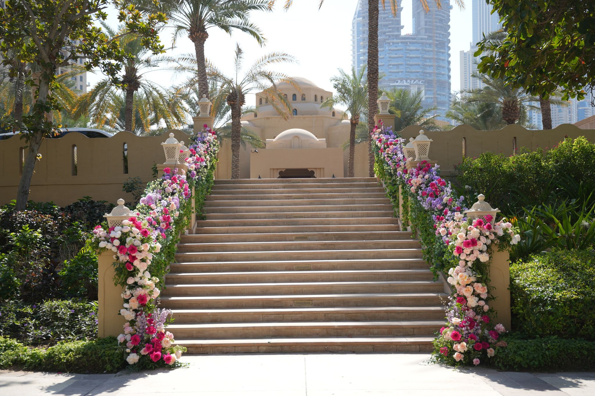 Grand sandstone staircase lined on both sides with rose garlands and lanterns at One&Only Royal Mirage Dubai