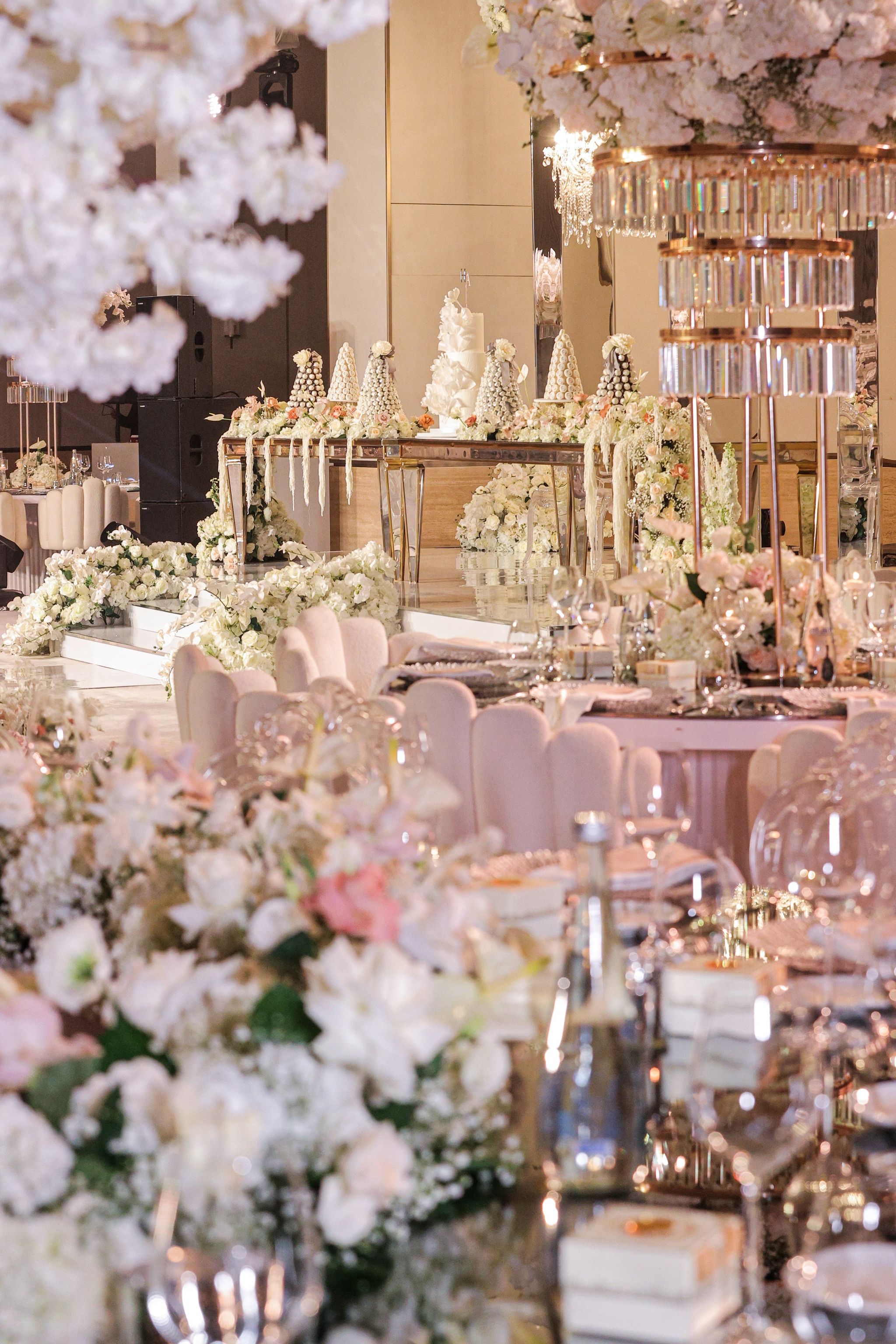 Blush and white florals framing a view across tables to croquembouche towers on the stage