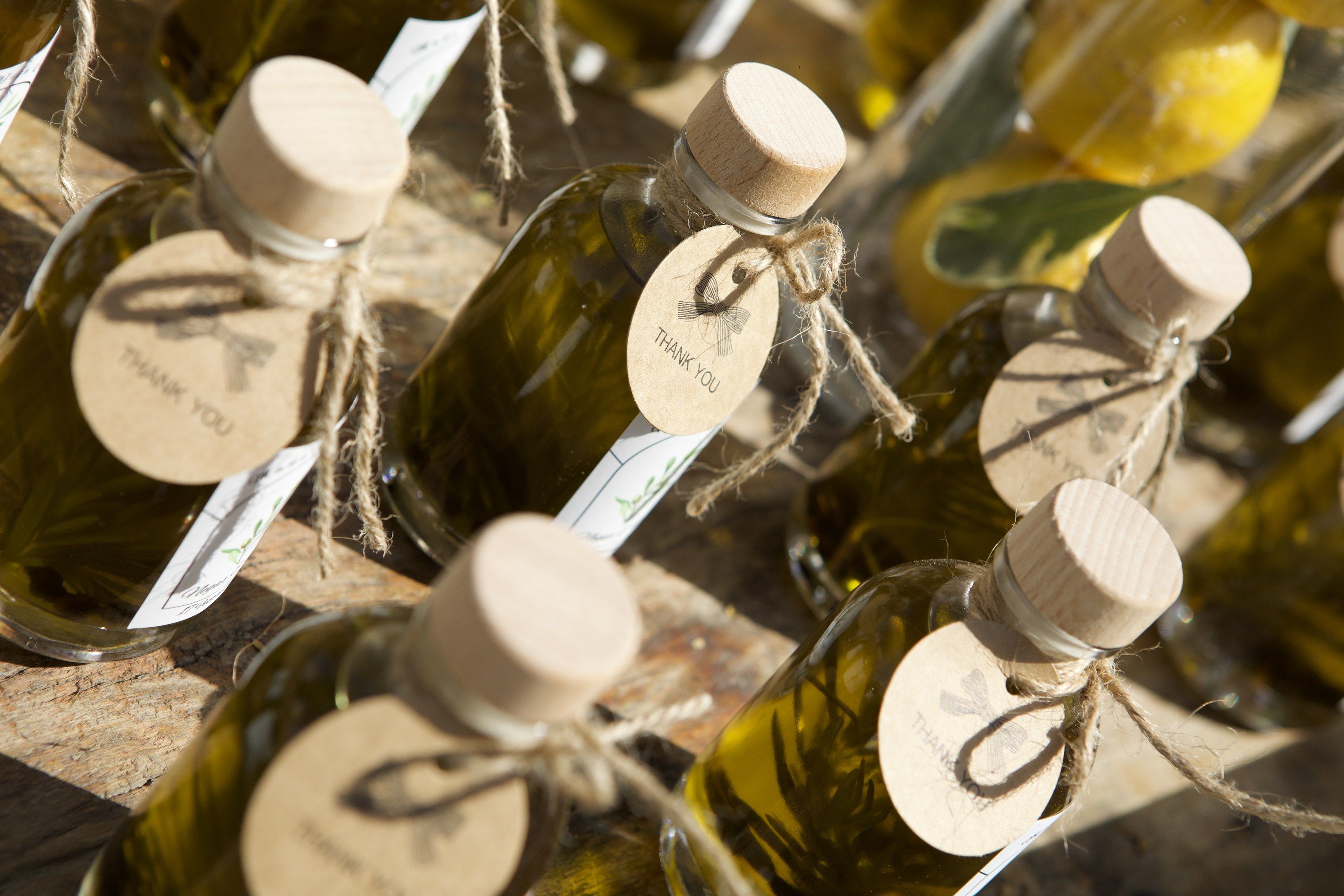 Corked olive-oil bottles tied with twine and kraft thank-you tags
