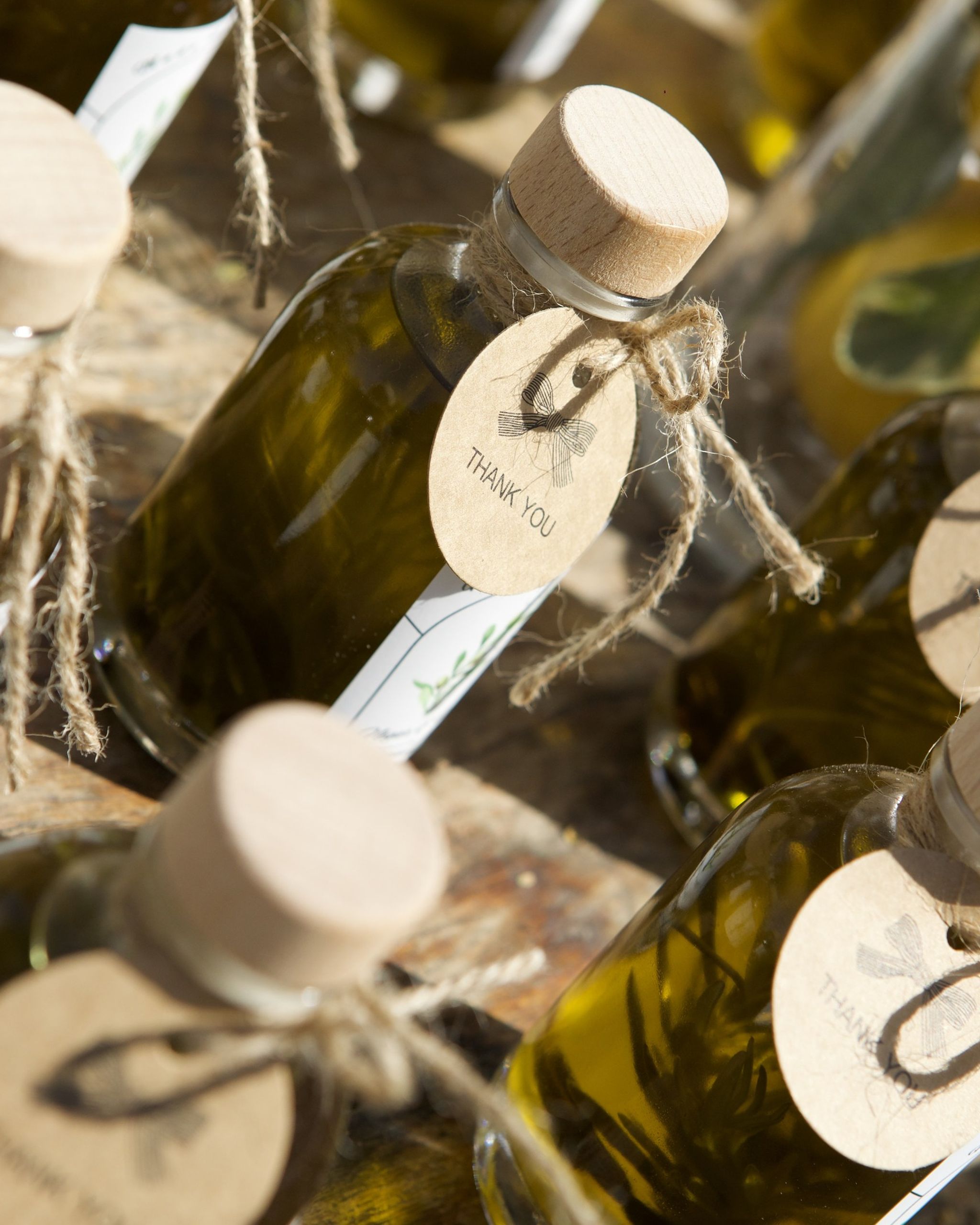 Corked olive-oil bottles tied with twine and kraft thank-you tags