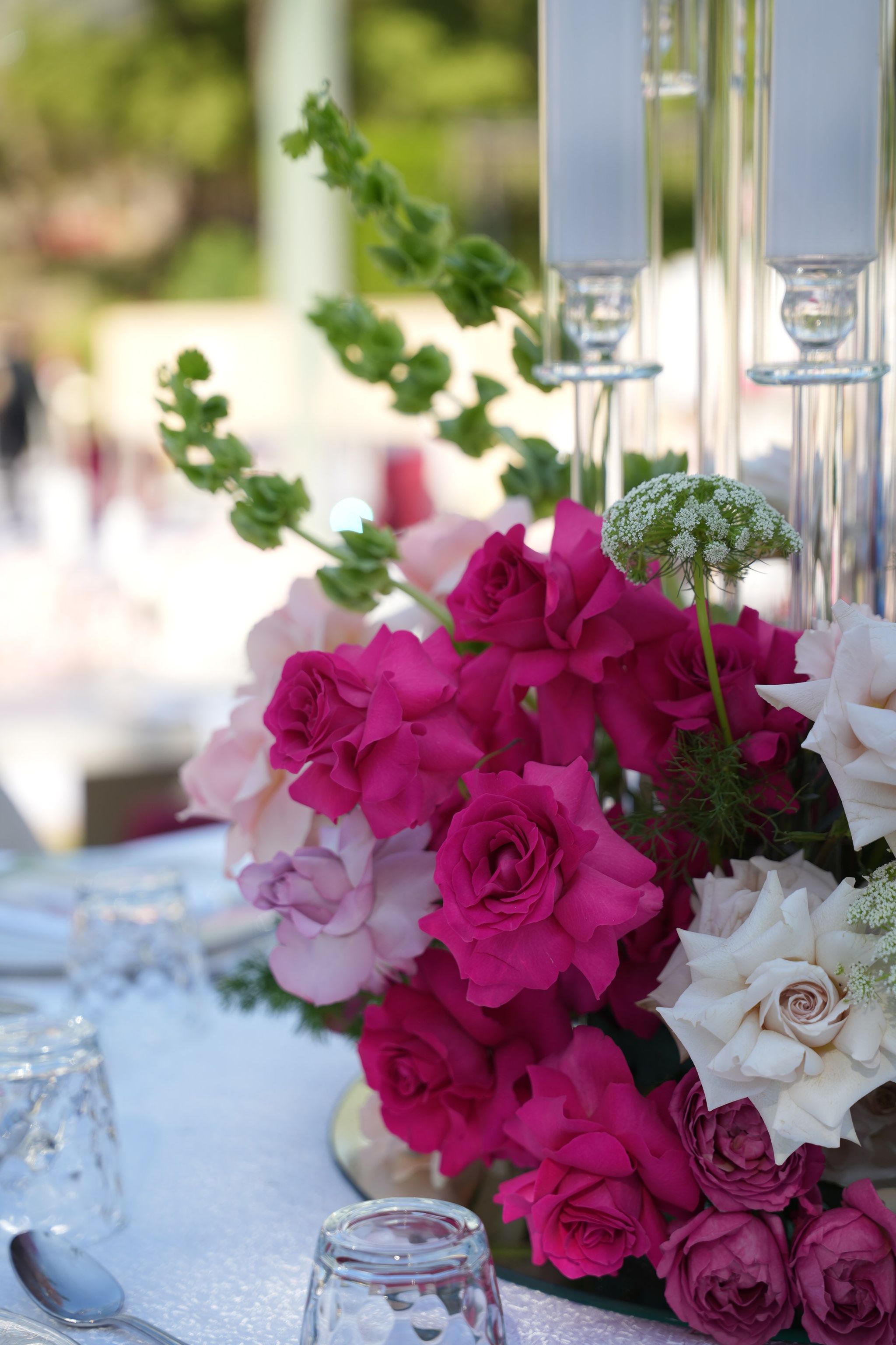 Close detail of fuchsia and ivory roses with Queen Anne's lace at a centrepiece base