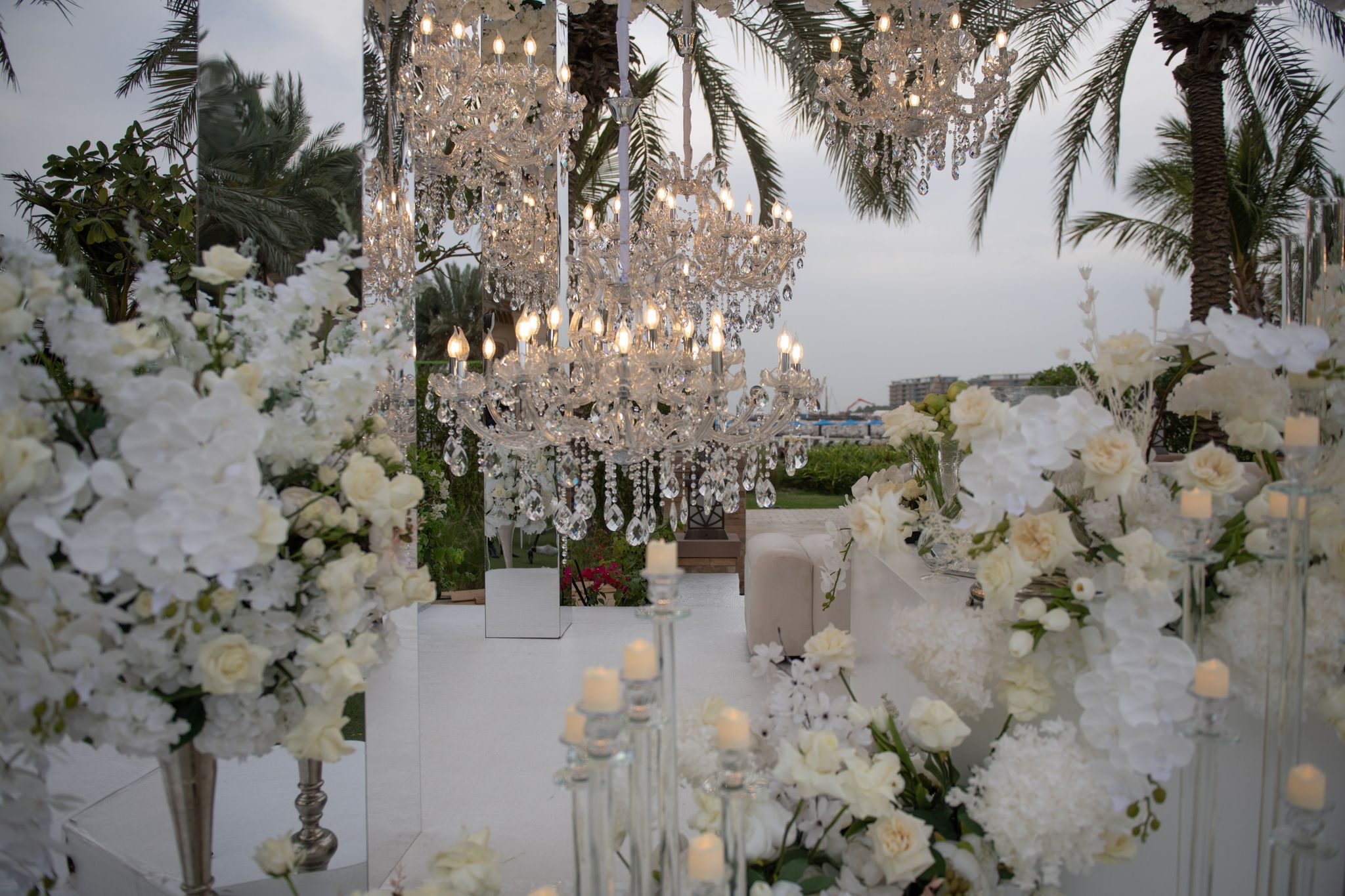 Crystal chandeliers suspended among mirrored panels, white orchids and candlelit glass stands