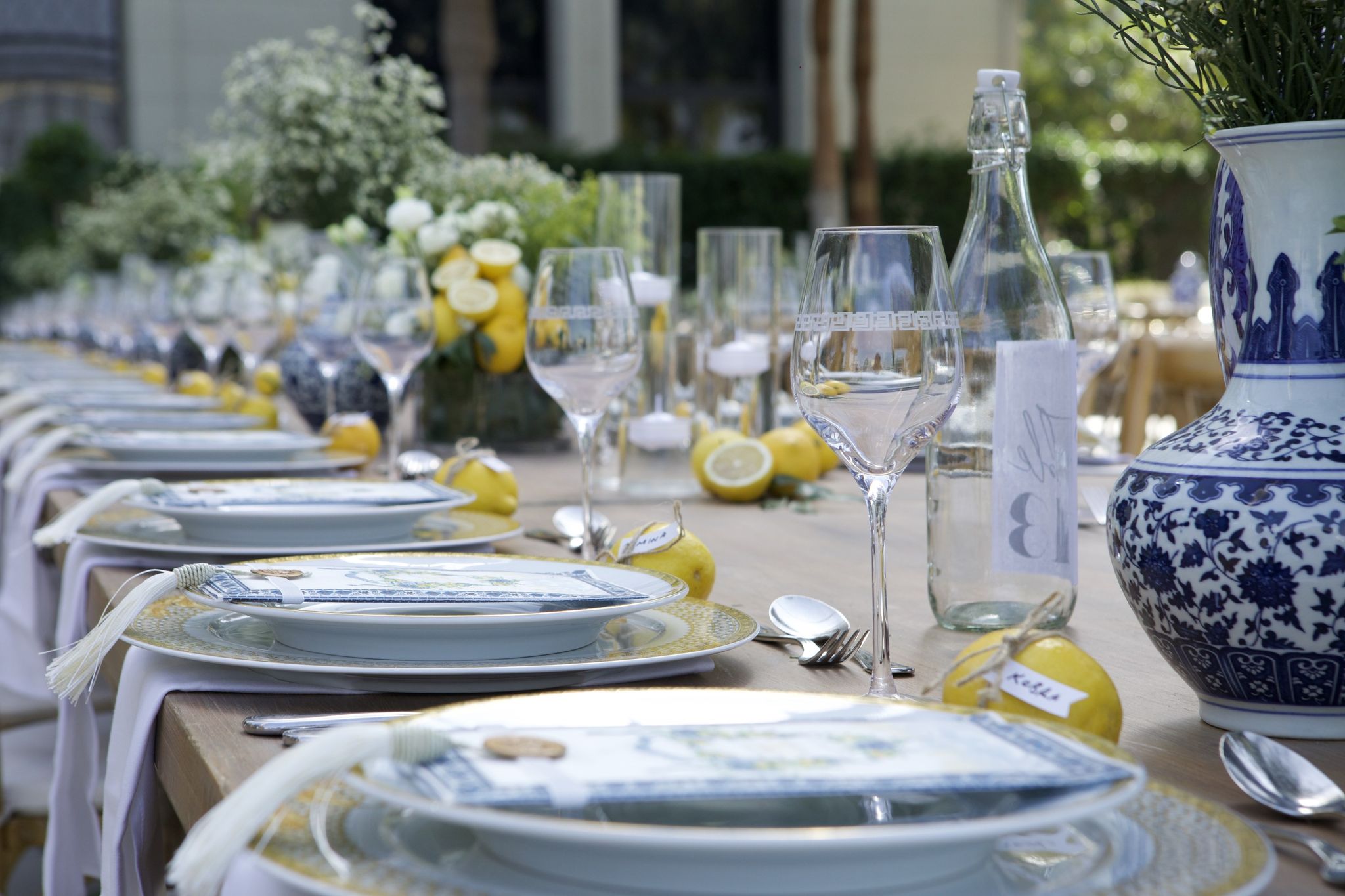 Lemons tagged as place cards beside crystal glasses and a blue-and-white vase