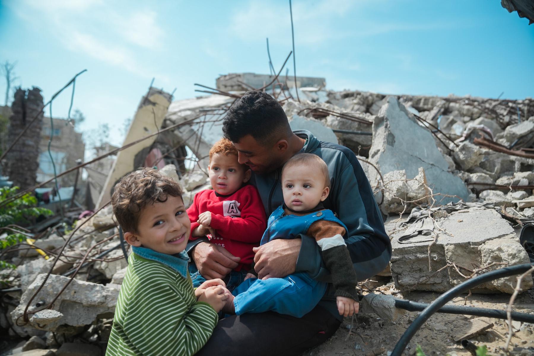 Mohammed sitting atop the rubble of his house with his three children.