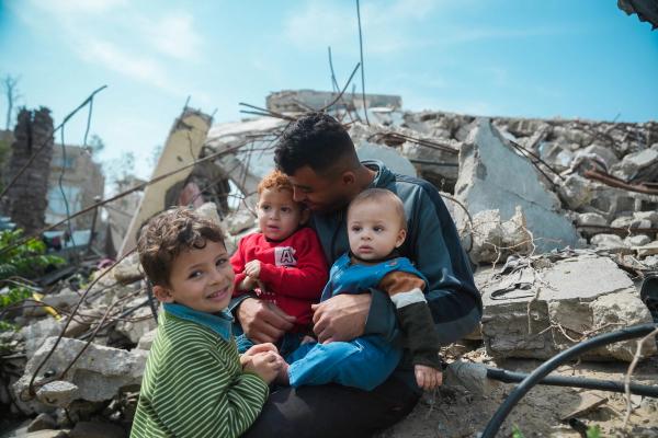 Mohammed sitting atop the rubble of his house with his three children.