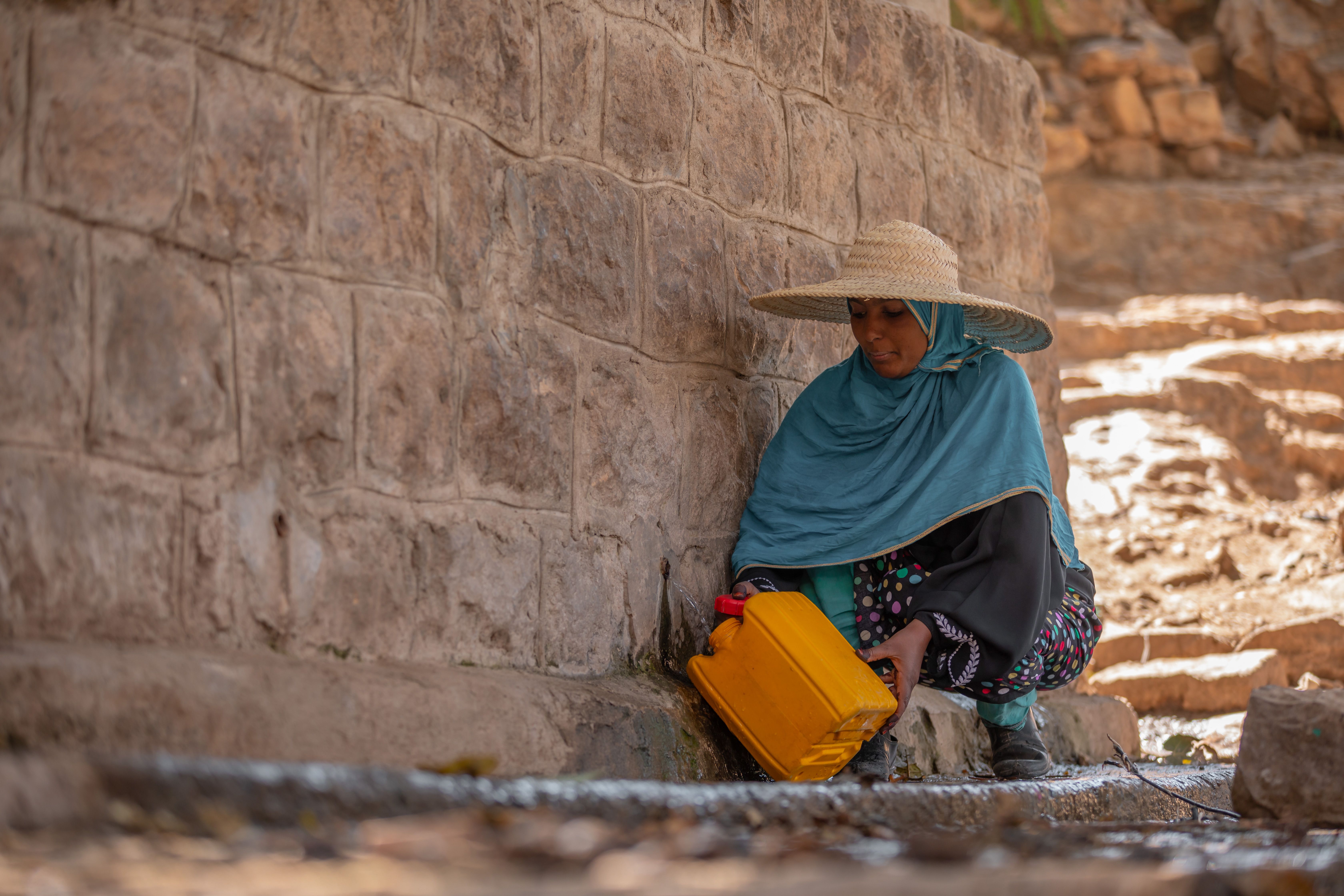 Yemen: Upon reaching the well, Rawya carefully fills her water container. The water is neither clean nor safe, but it is the only available source for her and her family. Photo:Ahmed ​Al-Basha / Oxfam Intermón