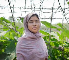 Shamsun stood in her yard where she grows vegetables