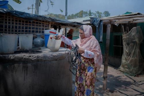 Romida collects water from the well in the refugee camp where she lives