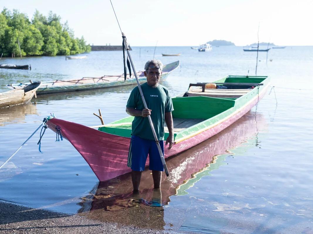 Mekko, Indonesia: Tasman (63) in front of the boat he uses for spear-fishing. He now struggles to catch enough fish to meet his daily needs as climate change has caused fish to move further and further out to sea. Photo: Vikram Sombu/Oxfam