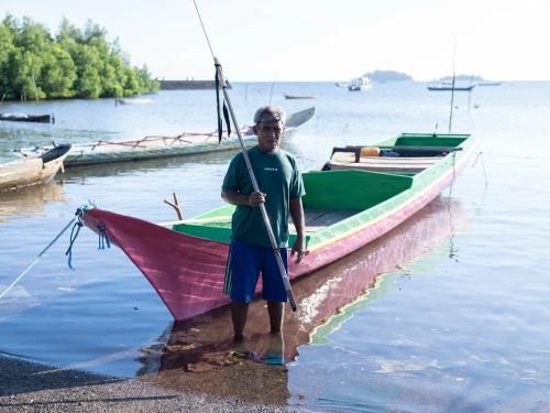 Mekko, Indonesia: Tasman (63) in front of the boat he uses for spear-fishing. He now struggles to catch enough fish to meet his daily needs as climate change has caused fish to move further and further out to sea. Photo: Vikram Sombu/Oxfam