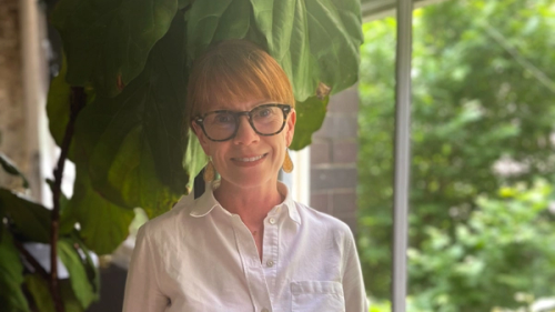 Australia: Jennifer Tierney stands in front of a window smiling. Photo: Oxfam