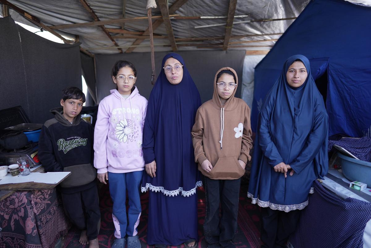 Rania and her family stand in front of her tent in a makeshift tent camp in Gaza