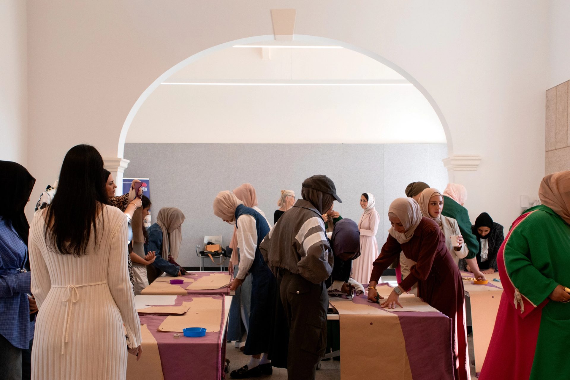 Many figures working with patterns on fabric in a big room