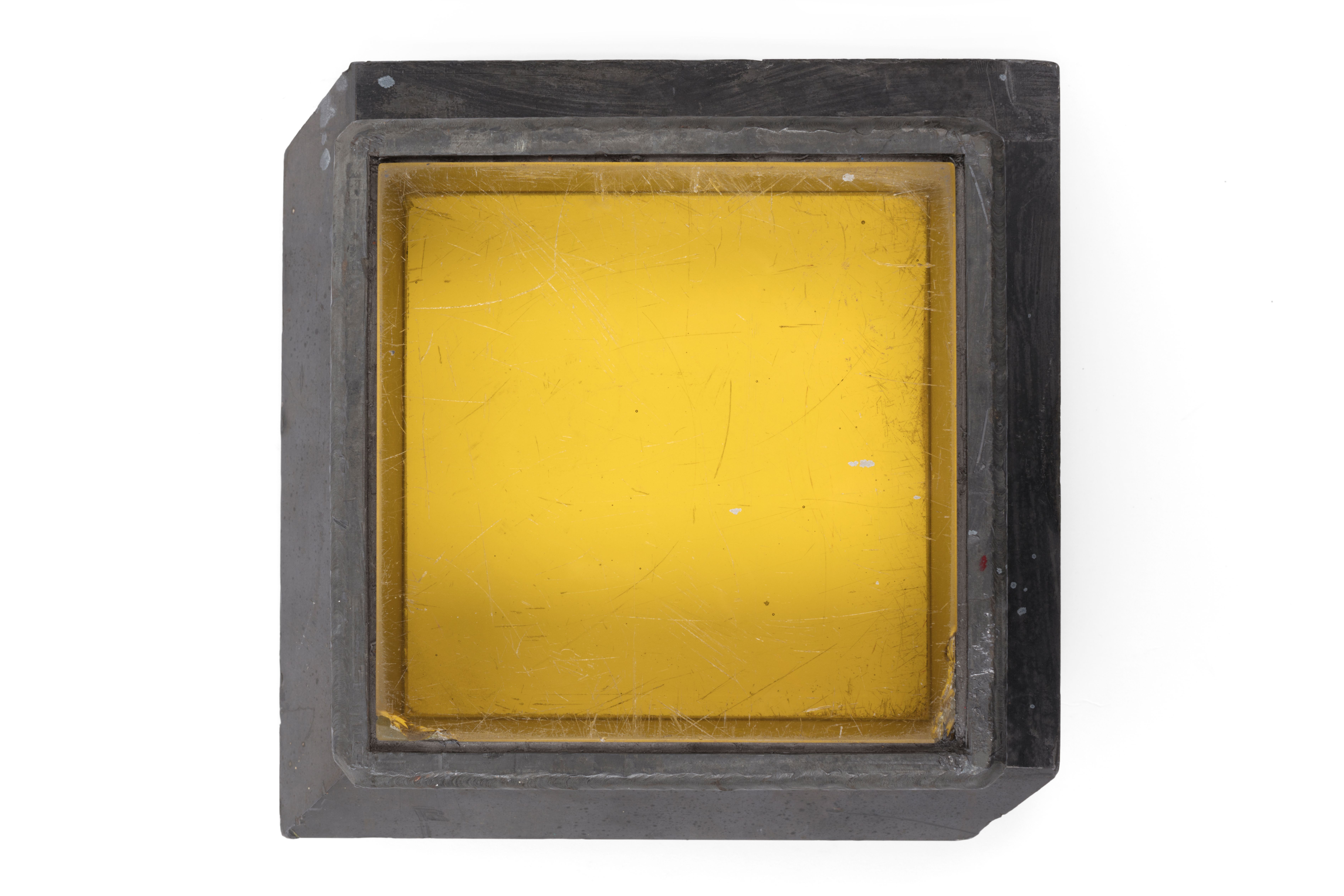 The thick glass has a yellow tinge from the presence of a small amount of cerium. Cerium is added to prevent the glass gradually turning brown from radiation damage. The glass is fitted within a grey lead frame.