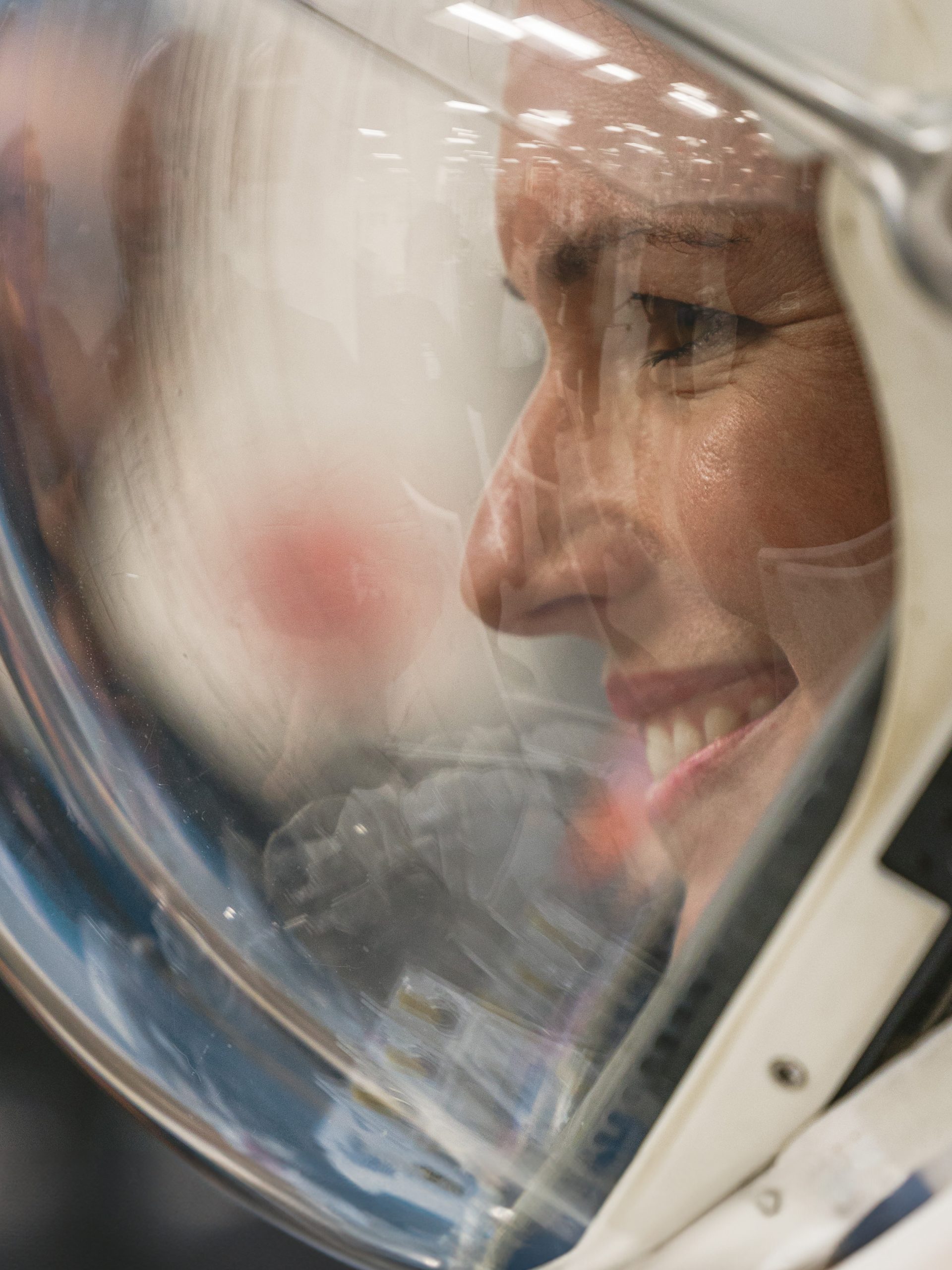 Side profile of woman in a space helmet, smiling.
