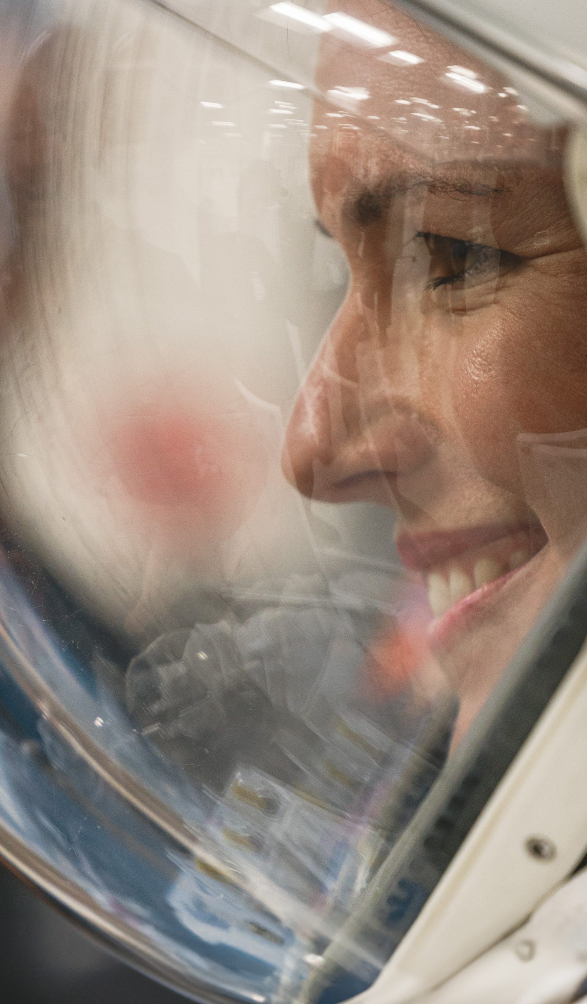 Side profile of woman in a space helmet, smiling.