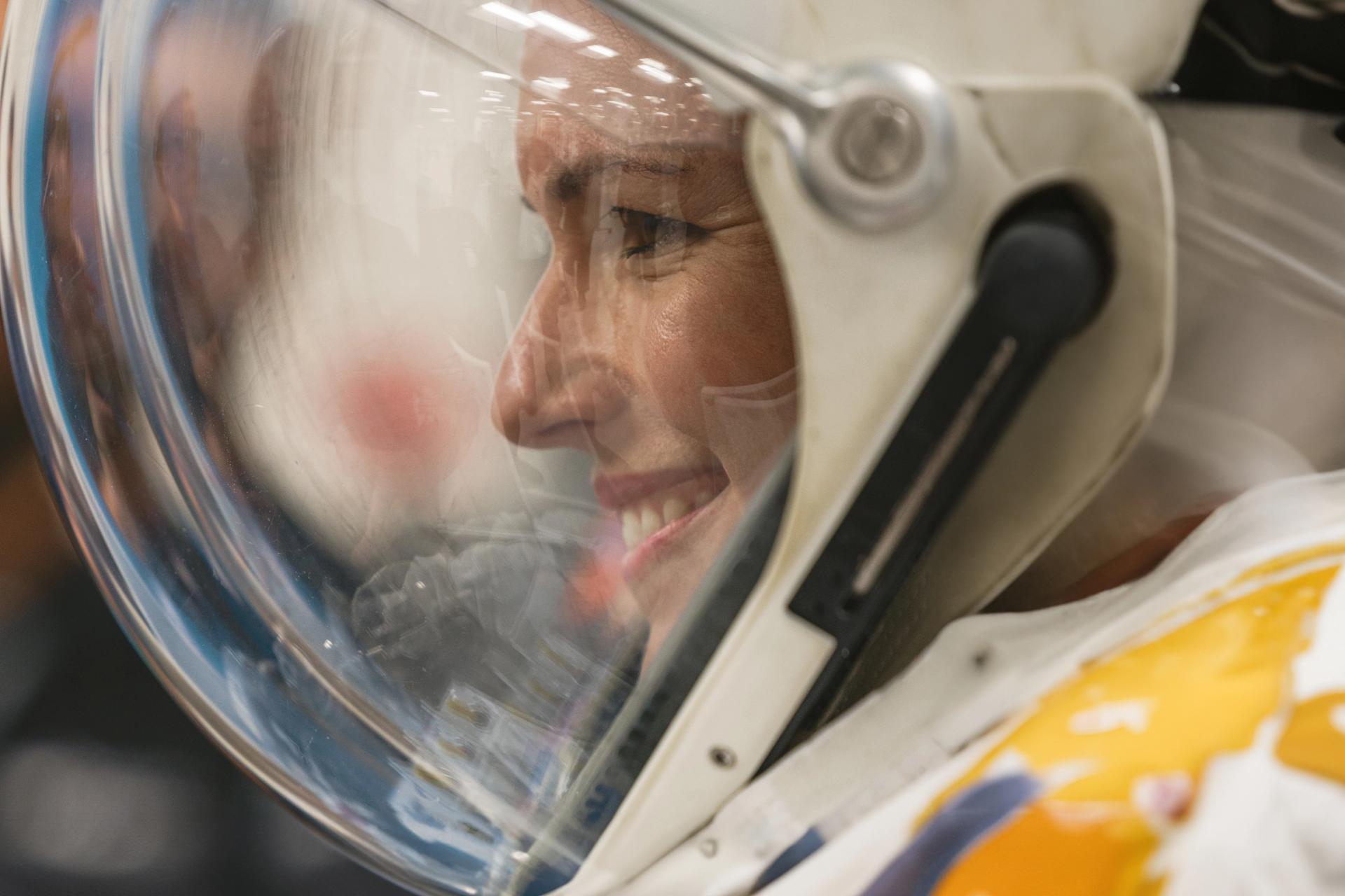 Side profile of woman in a space helmet, smiling.