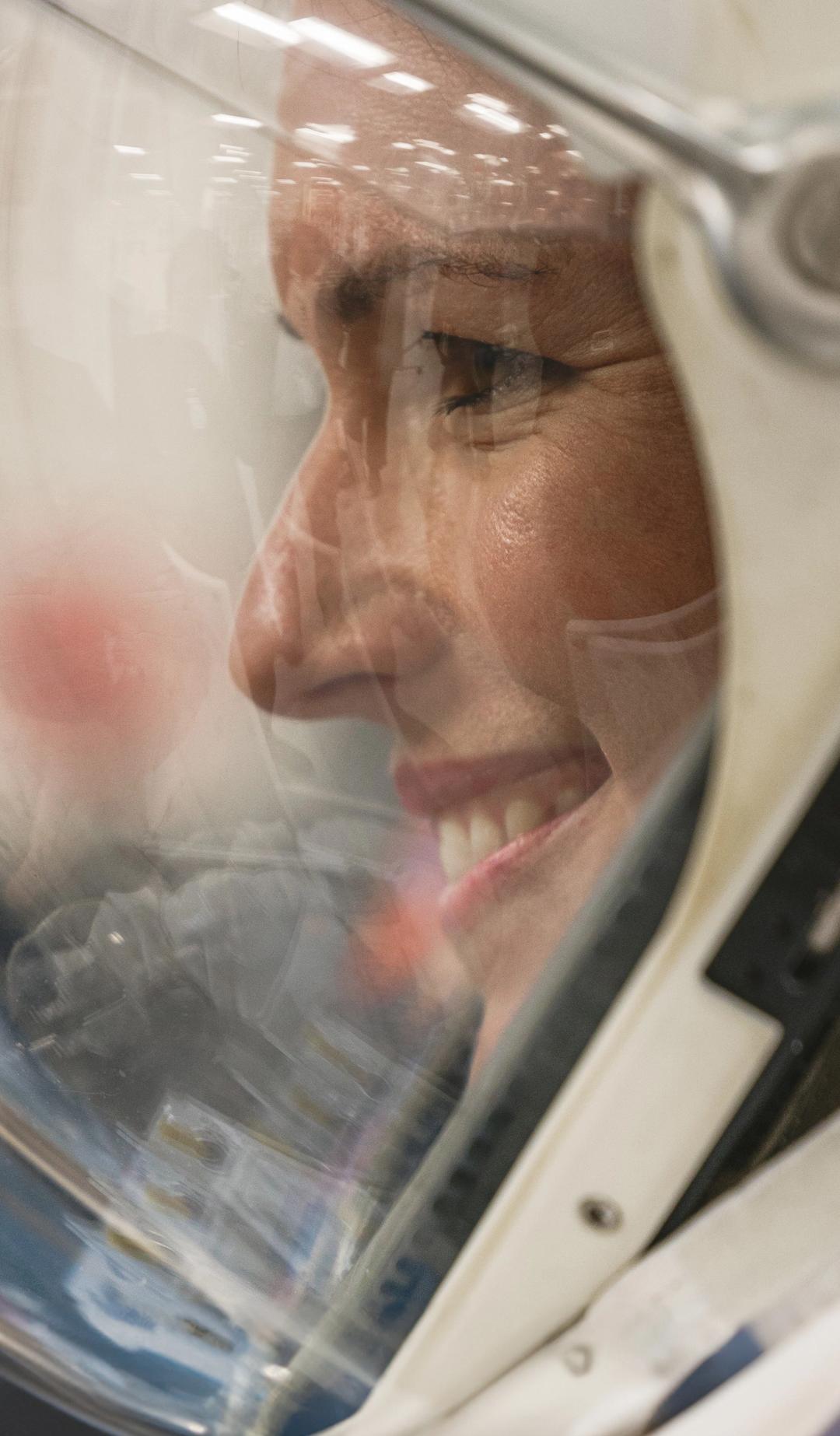 Side profile of woman in a space helmet, smiling.