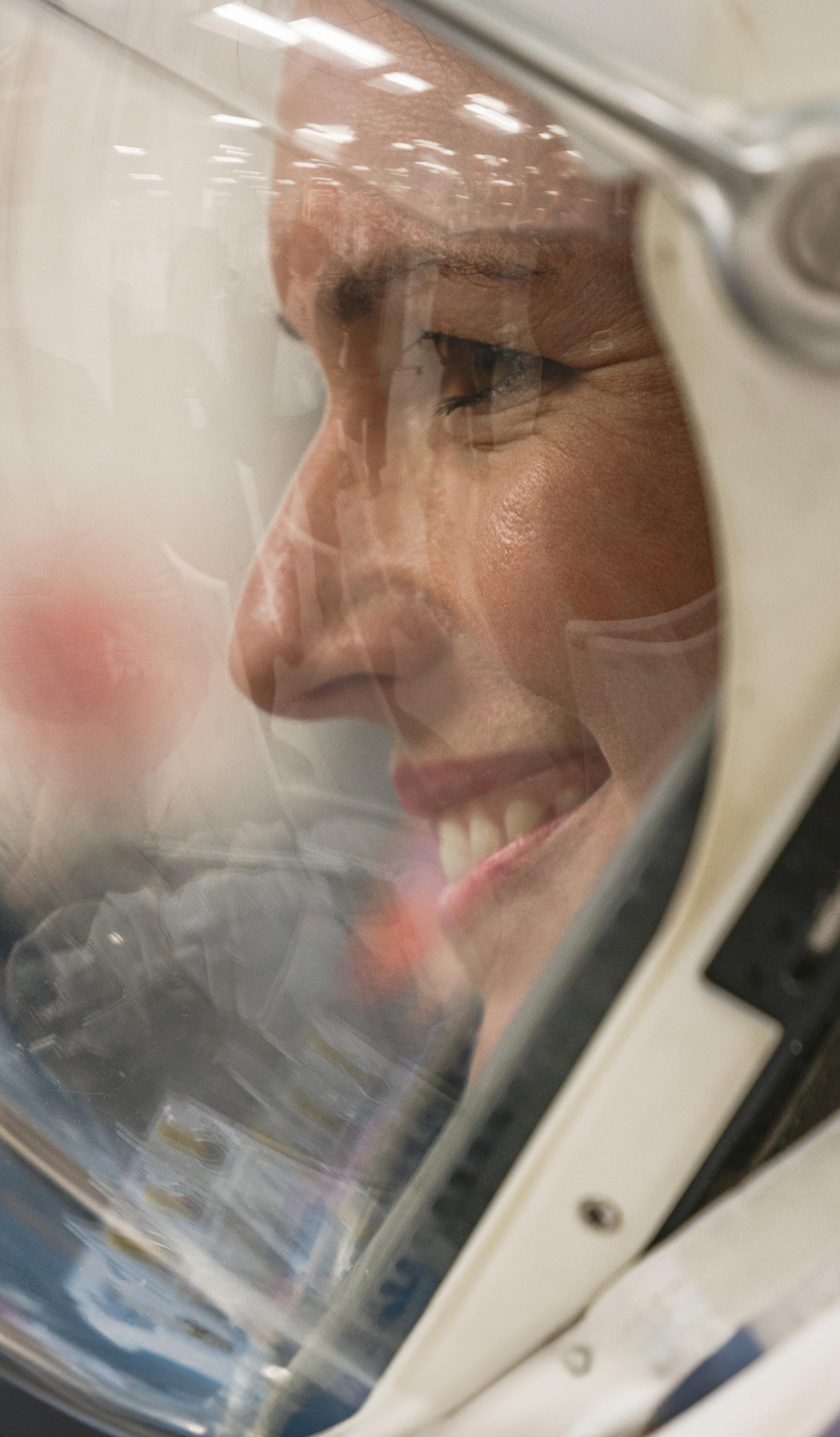 Side profile of woman in a space helmet, smiling.