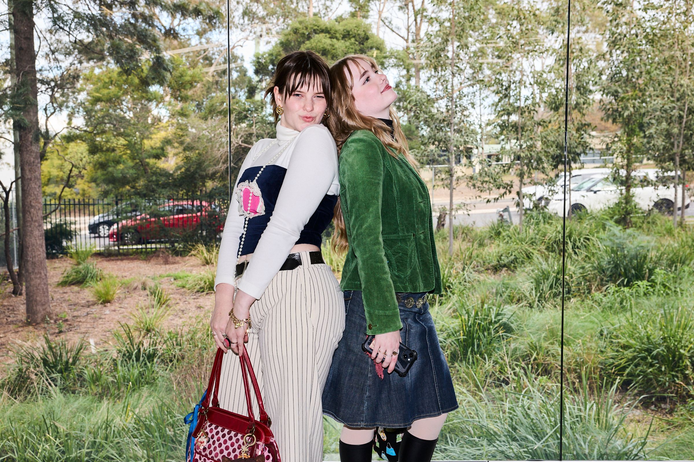 Two guests posing back to back against a glass window.