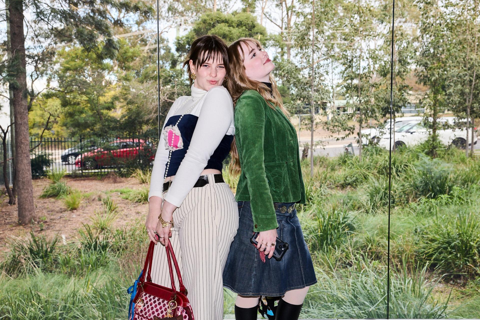 Two guests posing back to back against a glass window.