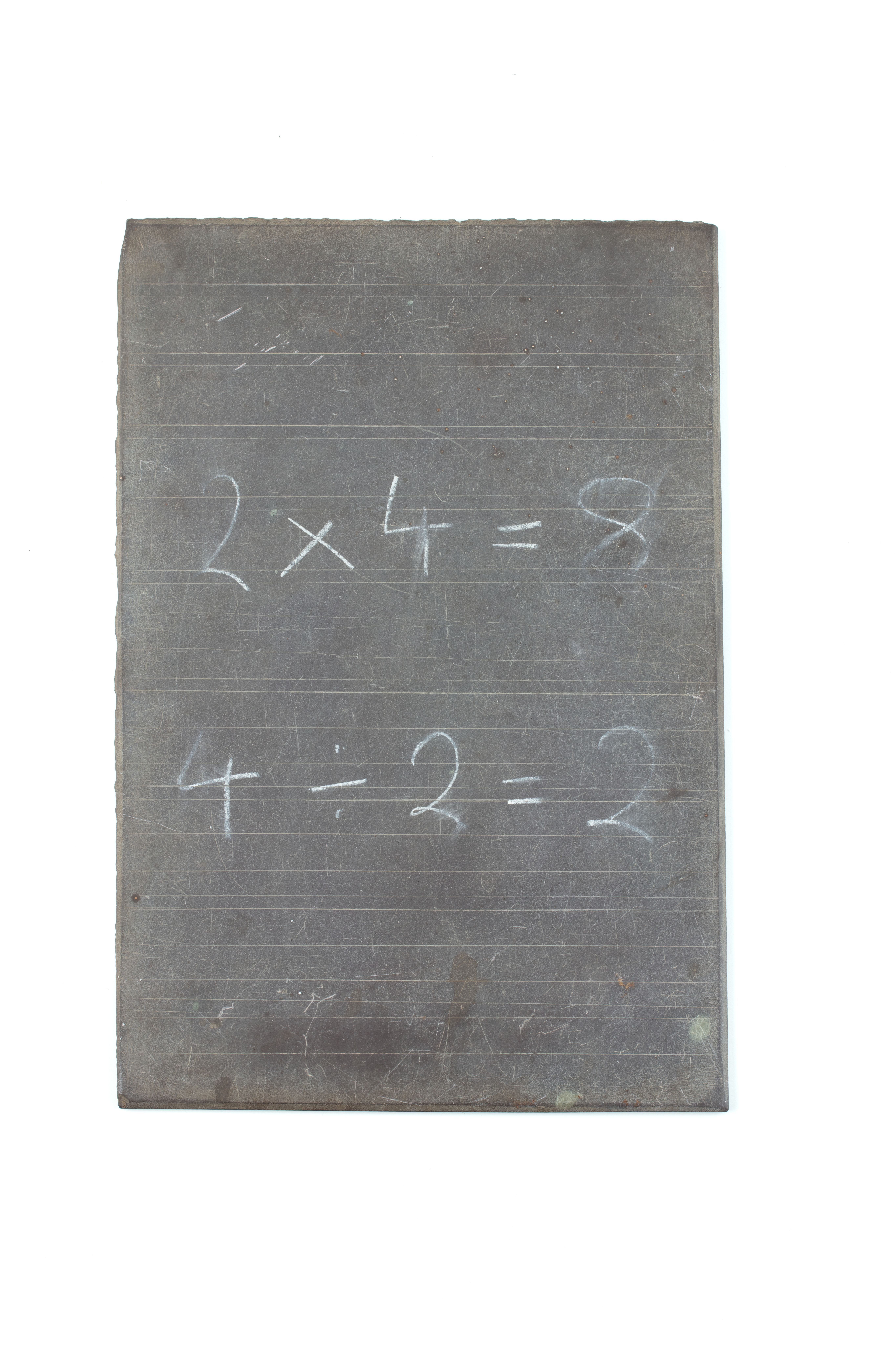 An old school slate, with fine ruled guide lines and some math calculations written on white chalk, '2x4=8, 4÷2=2'.