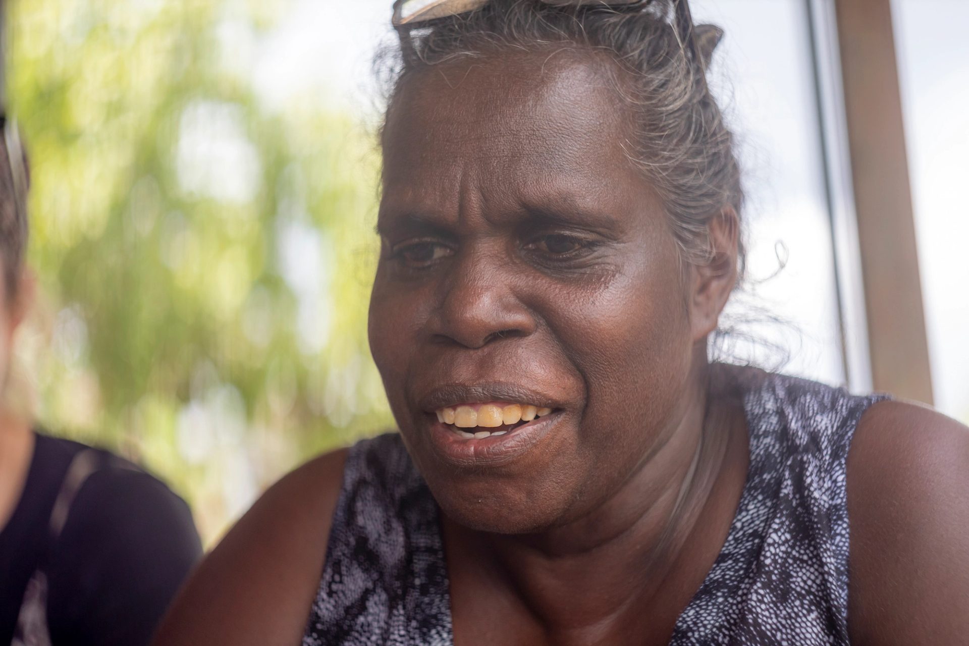 A woman lightly smiling and looking downwards.