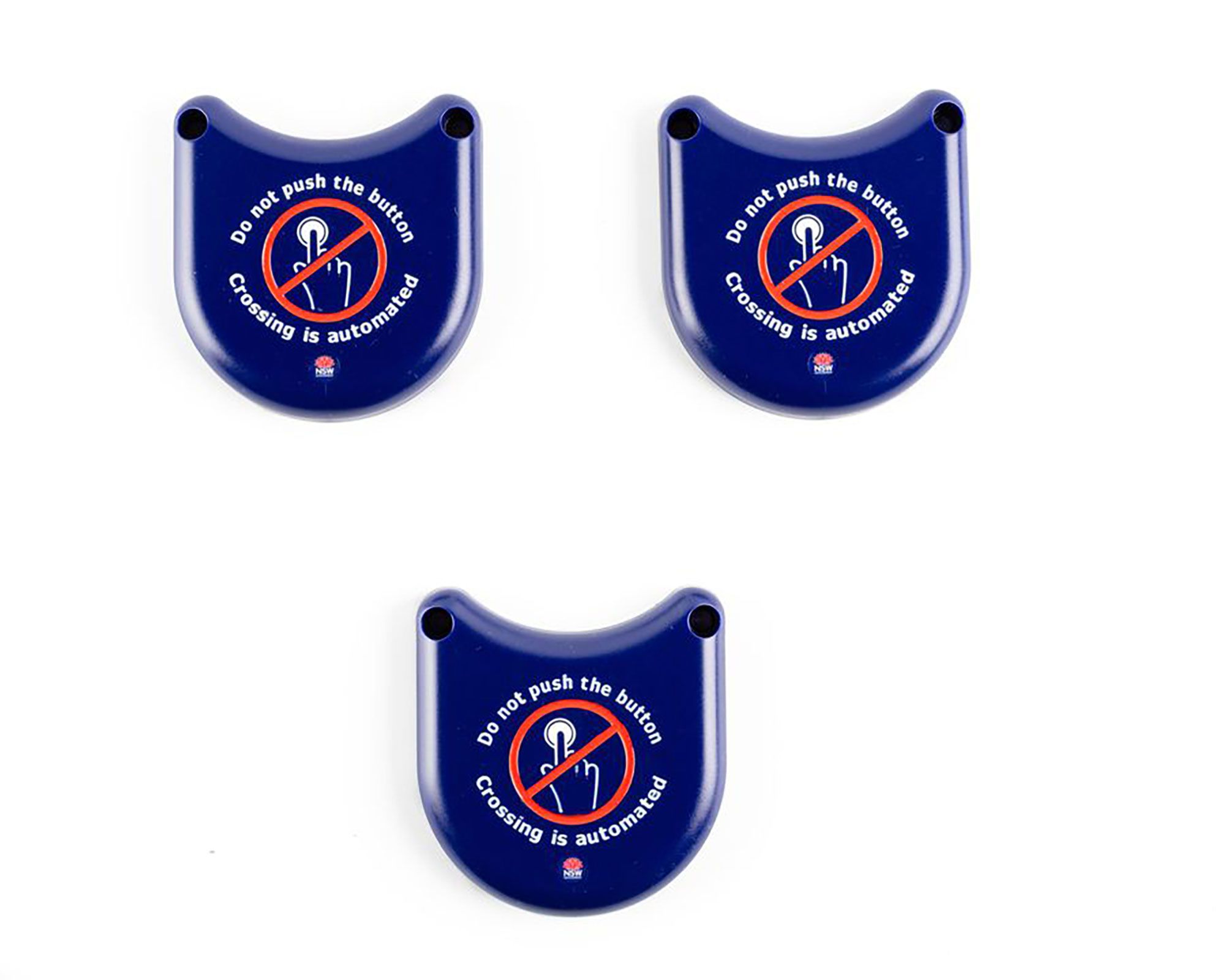 3 Solid plastic covers in dark blue. It has a curved design that can slot over the bottom half of the pedestrian traffic light buttons. It is designed to prevent people from touching the buttons surface as a safety measure due to the COVID-19 pandemic. Messaging on the button is designed to let pedestrians know not to touch surfaces as crossing have been automated. In the centre of the button is a graphic of a crossed out hand pushing a button to support text visually. It utilises the "do-not-do" graphic of a red circle with diagonal line through it.