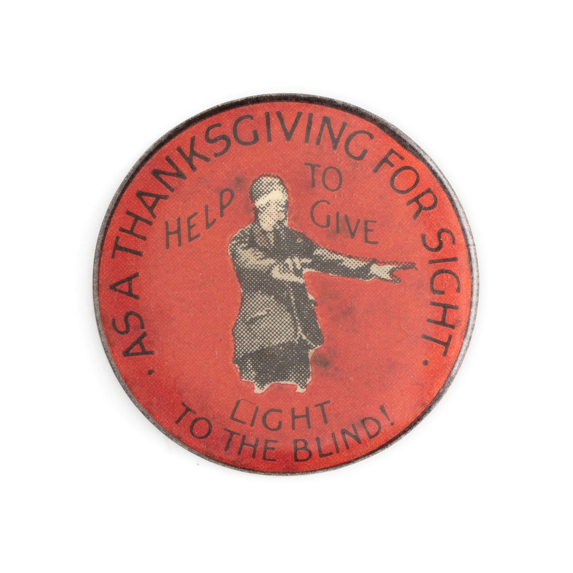 Red circular badge with monochrome image of man wearing blindfold with arms outstretched. Text in black: AS A THANKSGIVING FOR SIGHT HELP TO GIVE LIGHT TO THE BLIND. Text in red along black edge: A W PATRICK MAKER 440 RAE ST N FITZROY MELBNE.