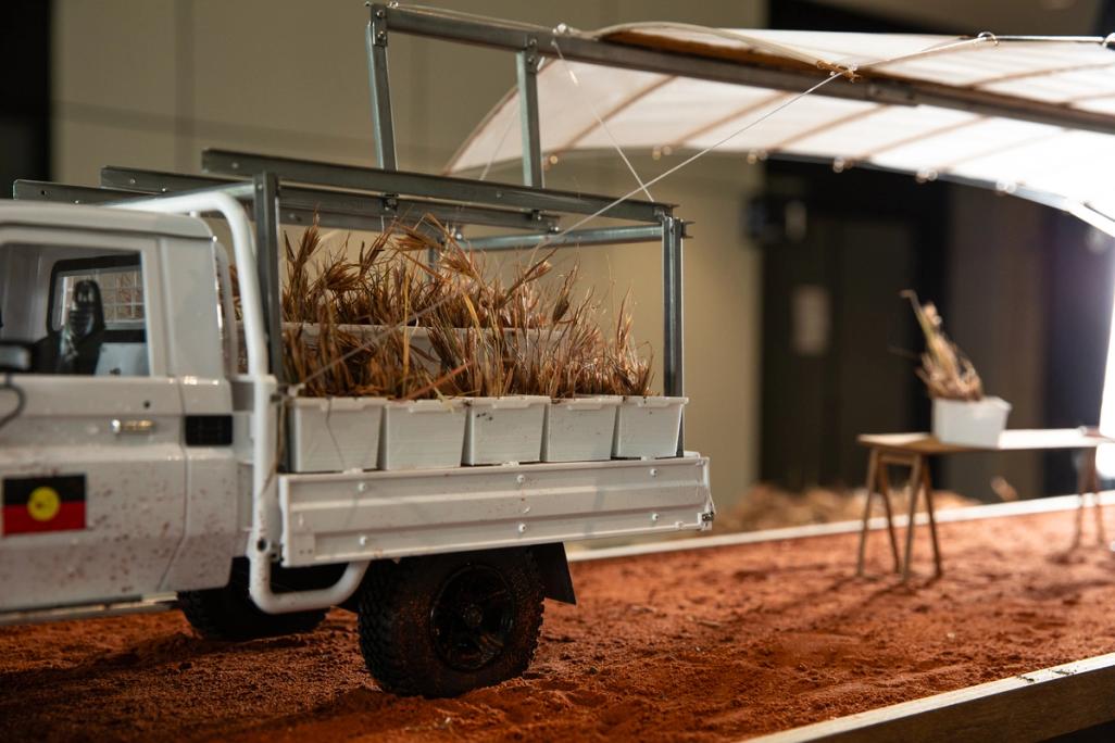 Miniature truck with contraptions sitting atop it, on a dirt road.