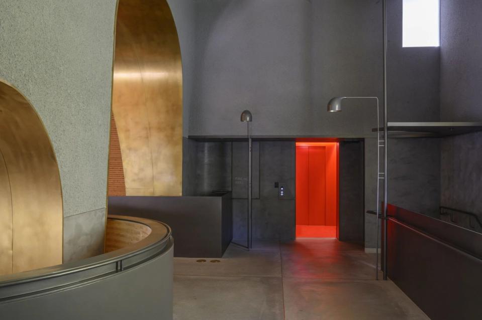 Interior of building with archways and curves, and a red lit doorway.